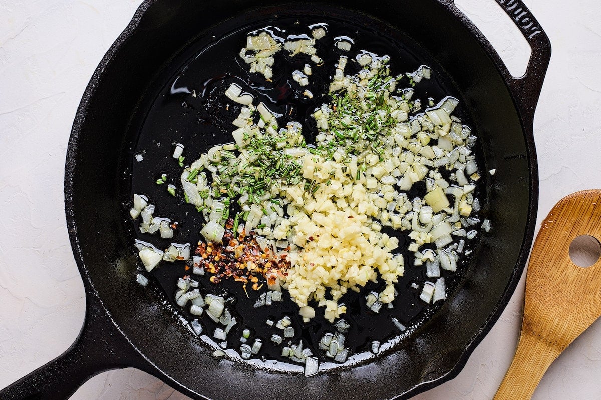 shallot, garlic, herbs, and crushed red pepper sautéing in olive oil in cast iron skillet.