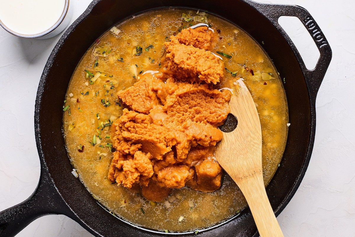 pumpkin pasta sauce in cast iron skillet with wooden spoon.