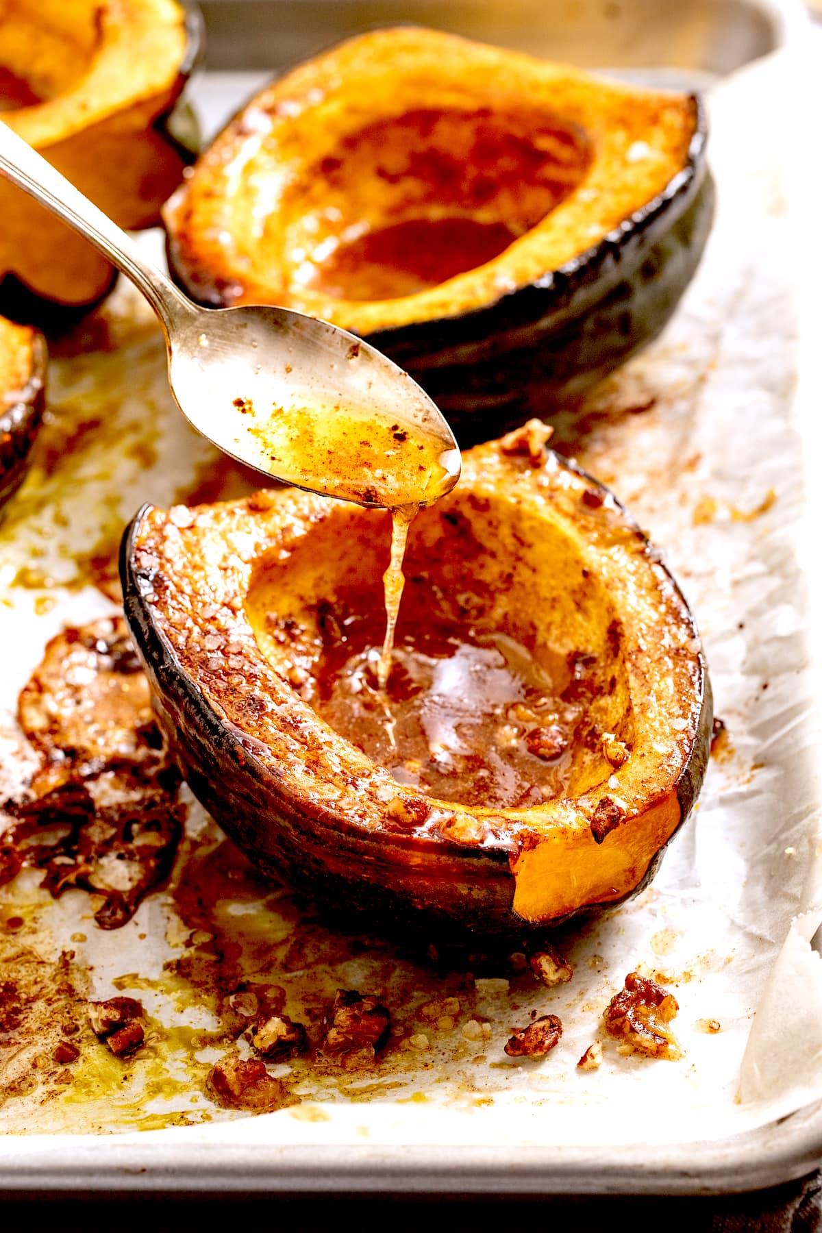 melted butter being spooned over roasted acorn squash.