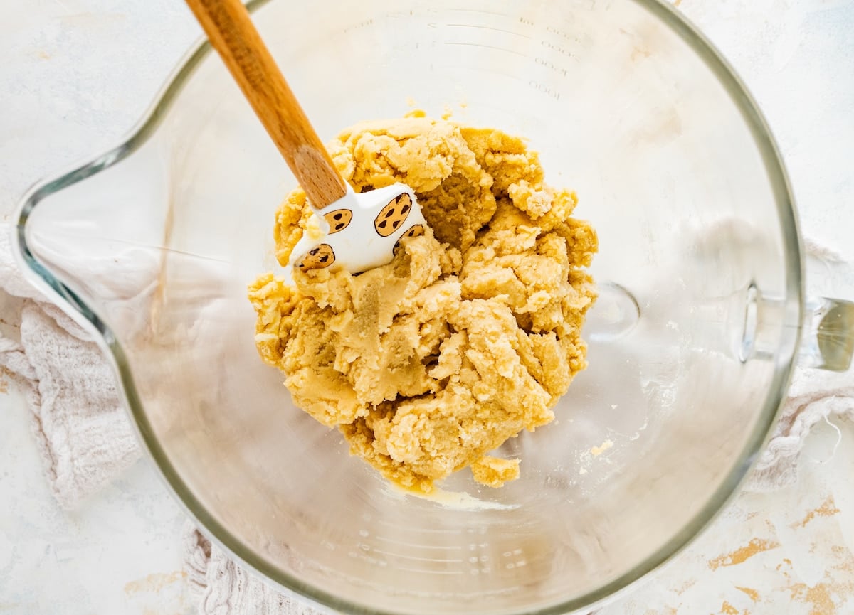 spritz cookie dough in mixing bowl with spatula.