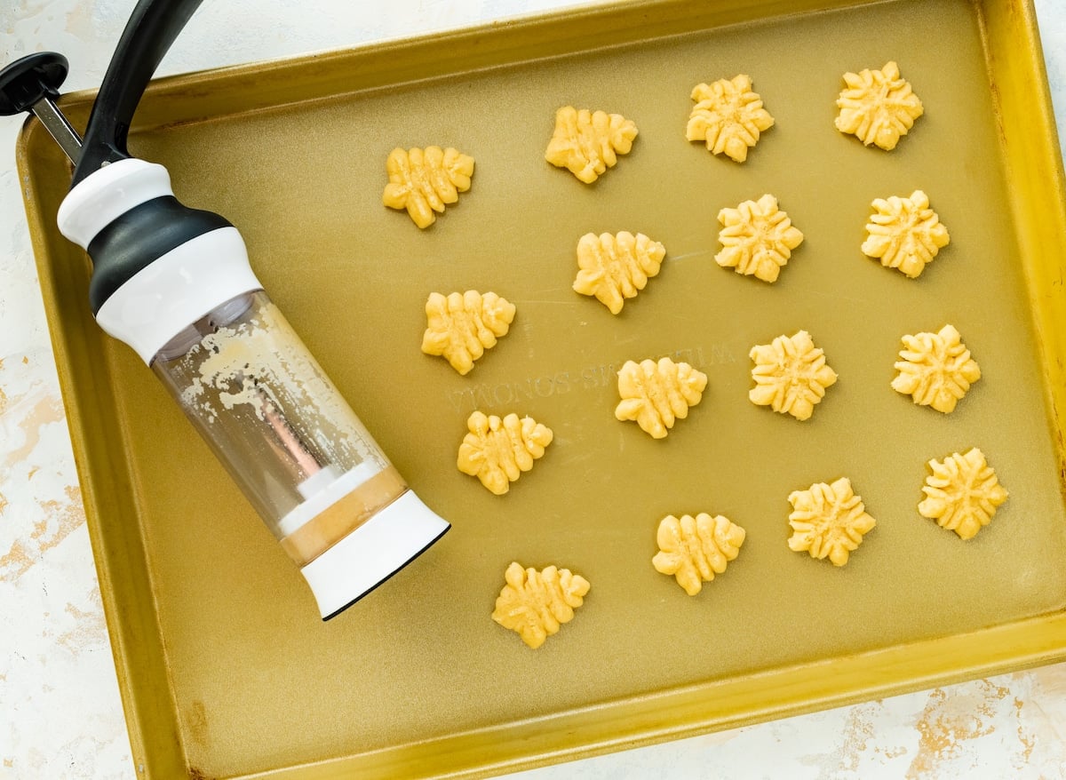 spritz cookies on baking sheet made with a cookie press.