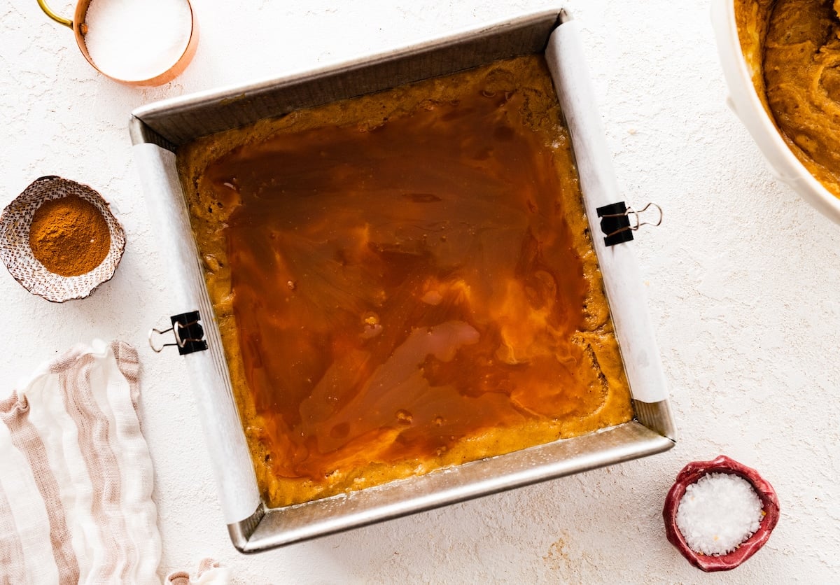 snickerdoodle blondie batter in pan with a layer of salted caramel sauce.