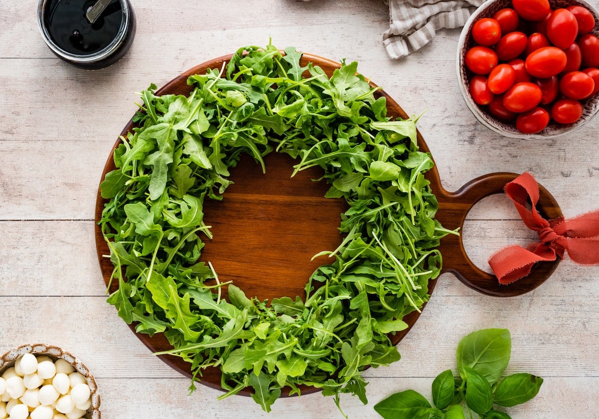 arugula in shape of wreath on wood board.