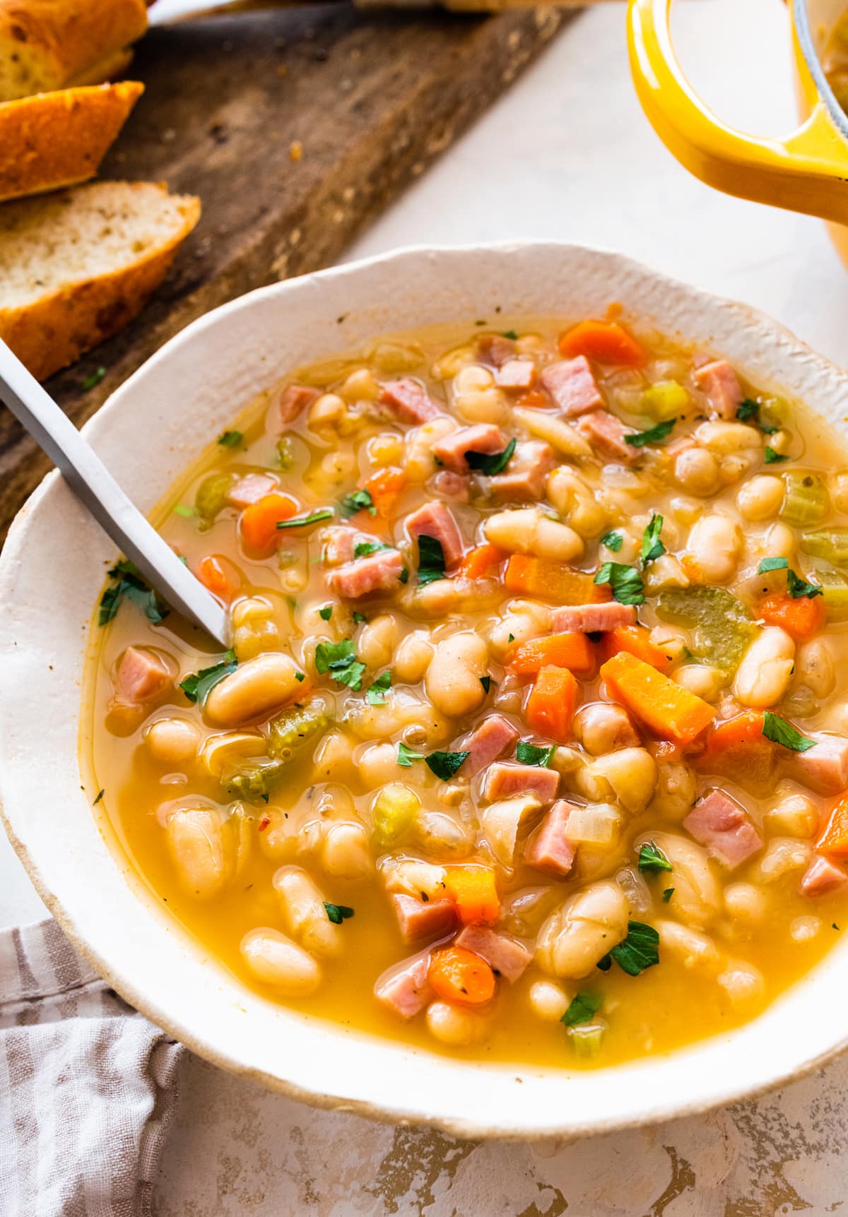 close up of ham and bean soup in bowl with spoon.