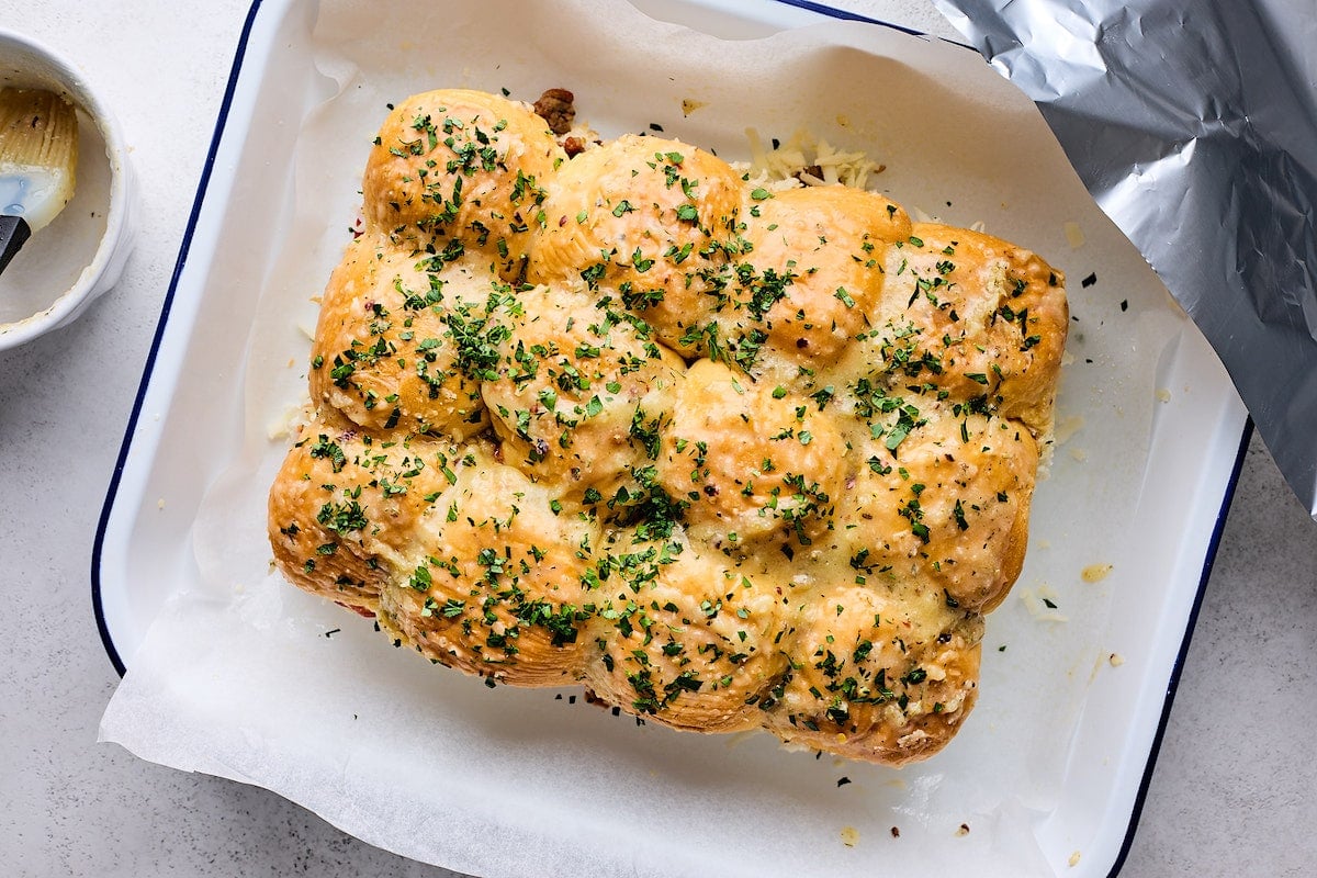 garlic butter being spread over pizza sliders.