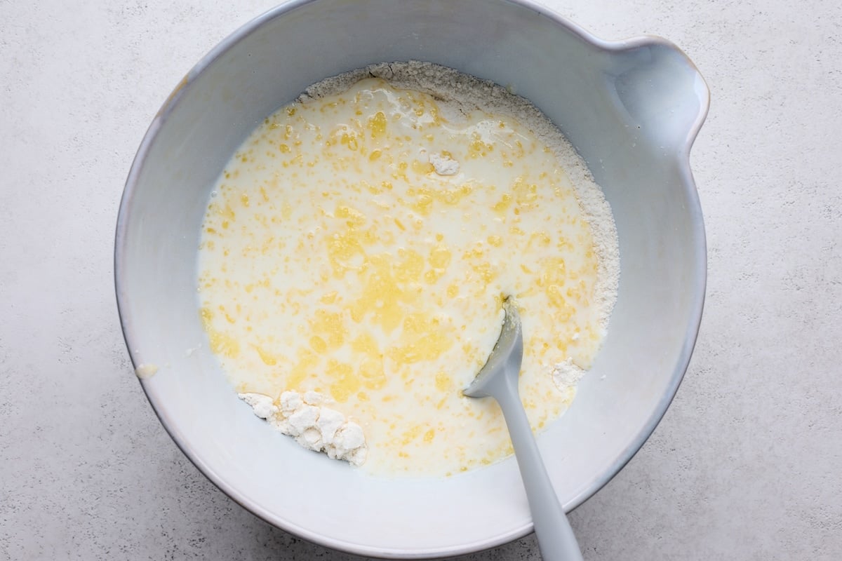 using a spatula to mix dry ingredients into melted butter and buttermilk to make drop biscuits.