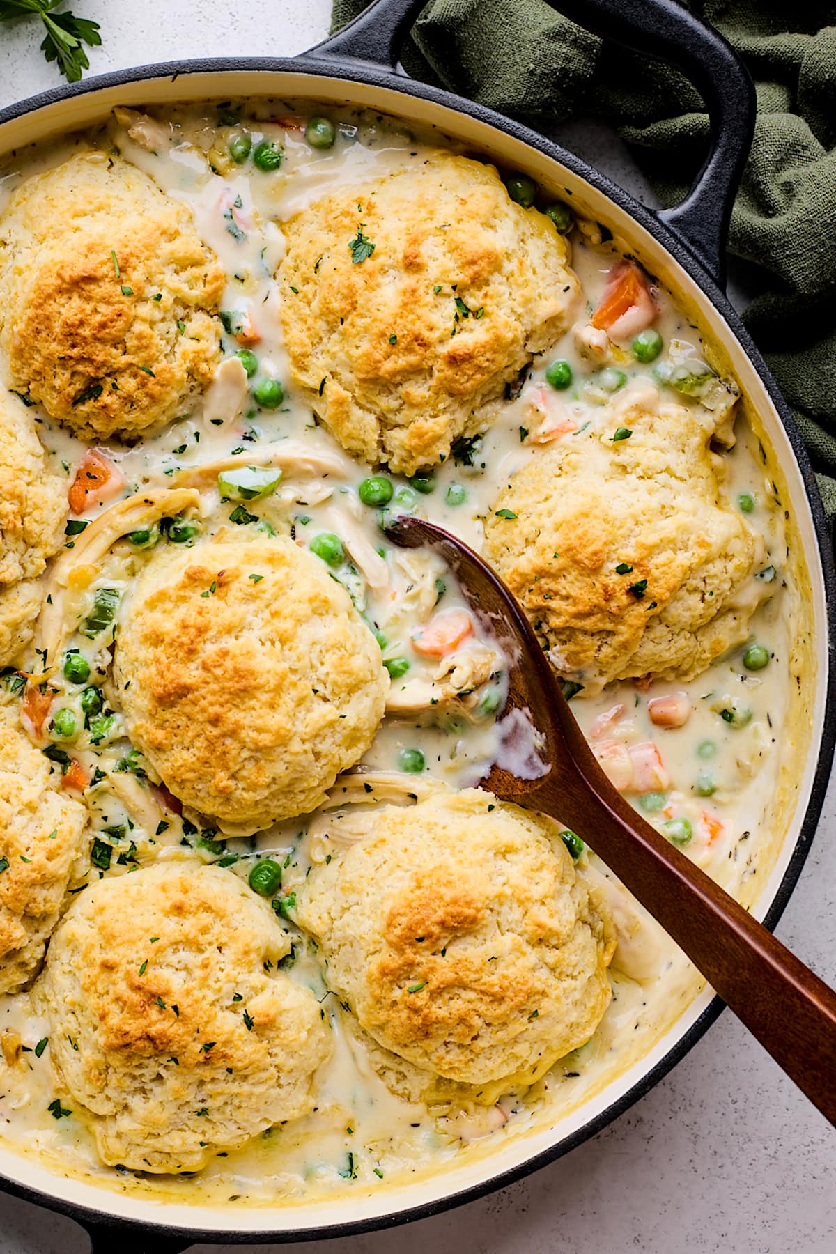 chicken pot pie with biscuits in skillet with serving spoon.