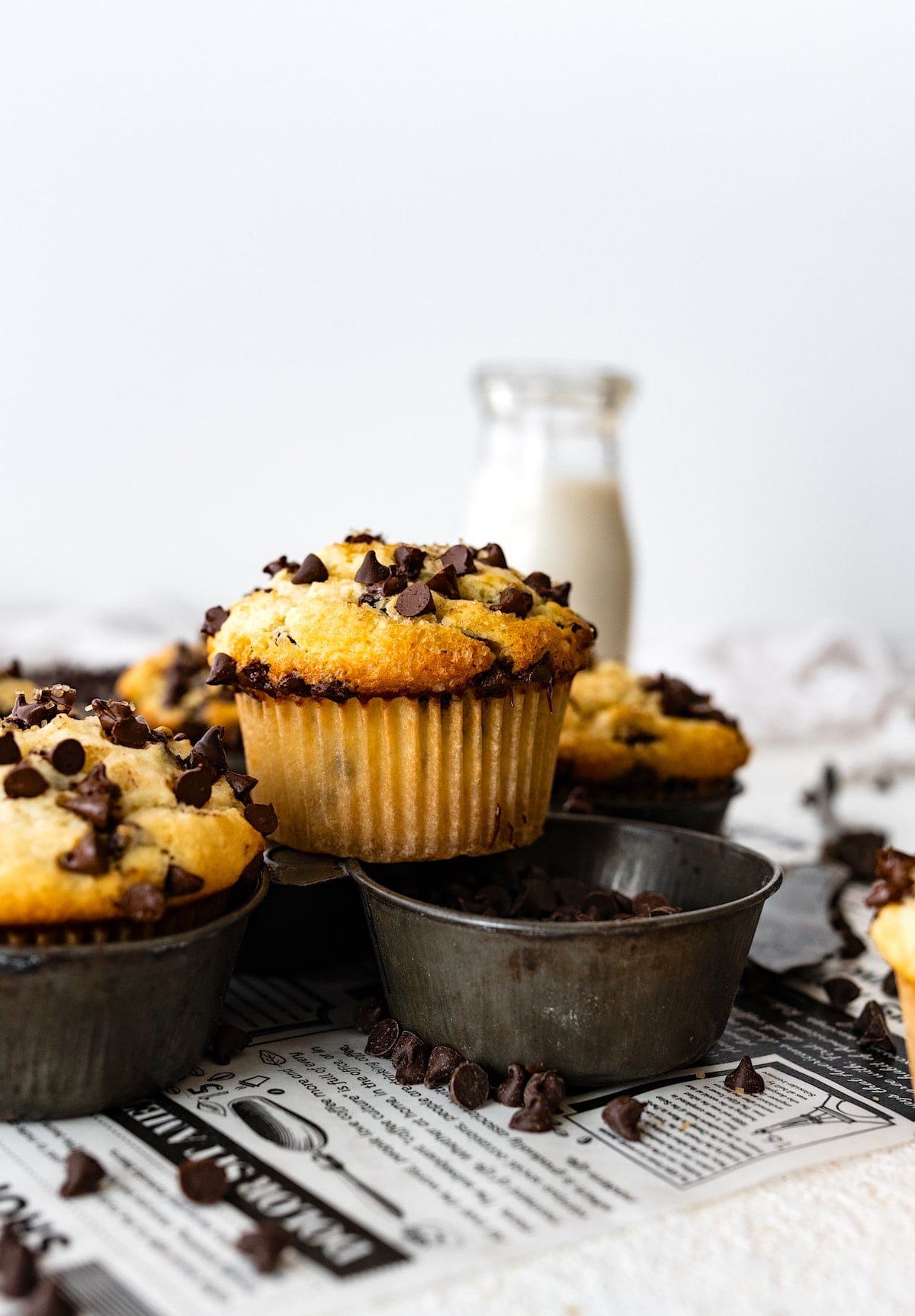 chocolate chip muffin sitting on top of muffin tin with mini chocolate chips.