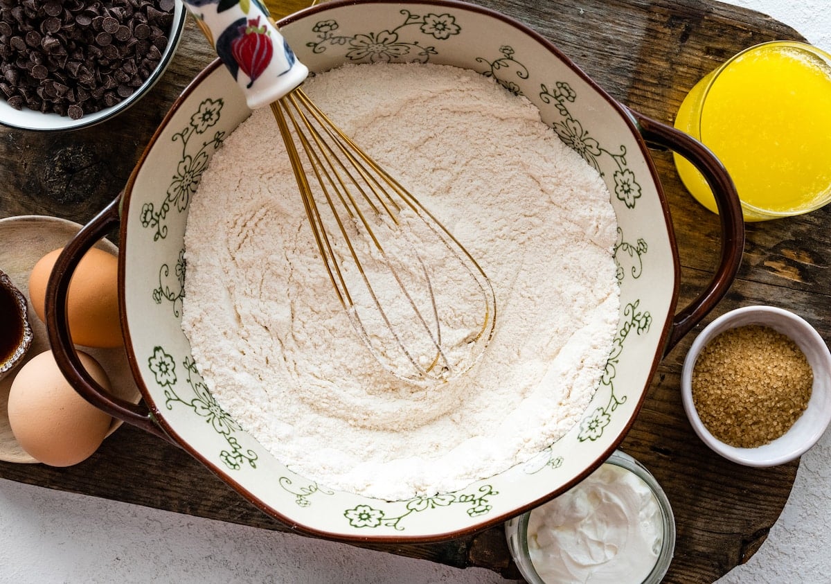 dry ingredients being whisked together in mixing bowl to make chocolate chip muffins.