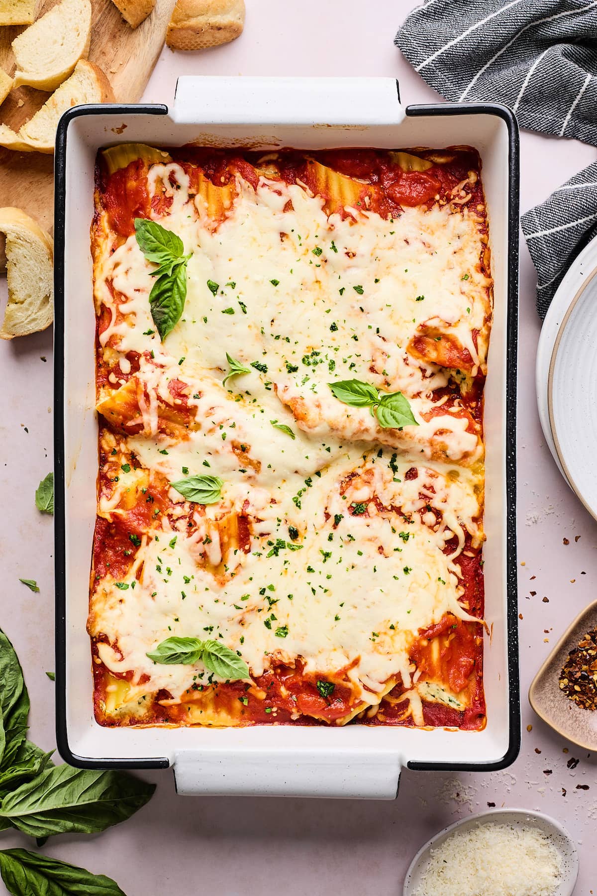 manicotti in baking dish with fresh basil.
