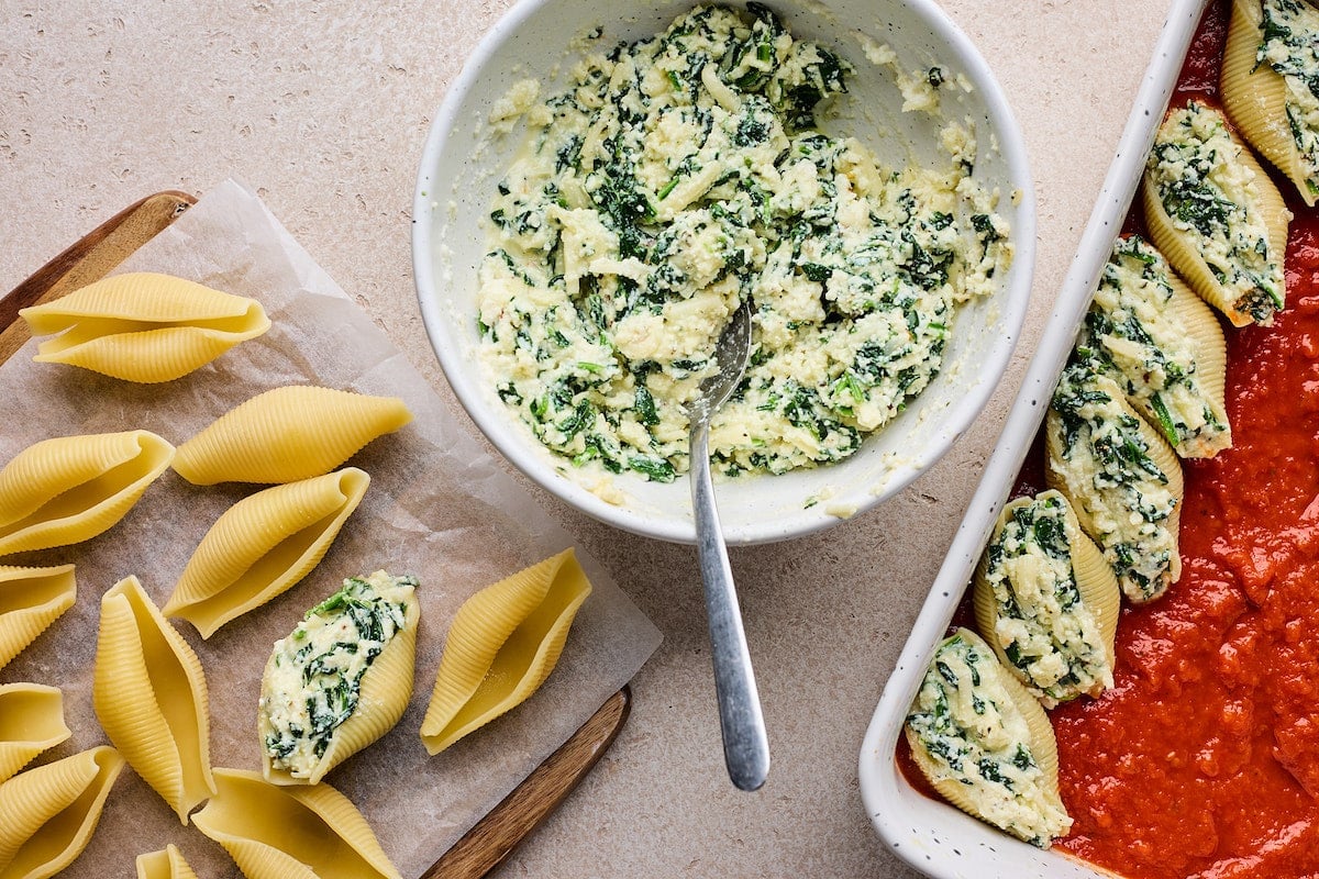 stuffed shells being filled with ricotta cheese filling.