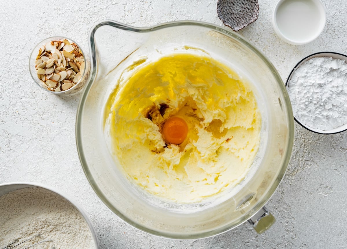 creaming butter, sugar, egg, and vanilla together in mixing bowl to make almond cookies.
