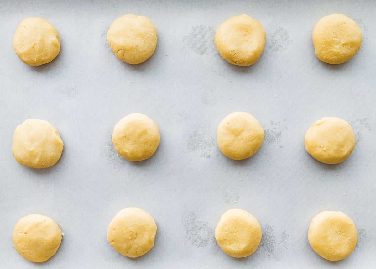 almond cookie dough balls on baking sheet with parchment paper.