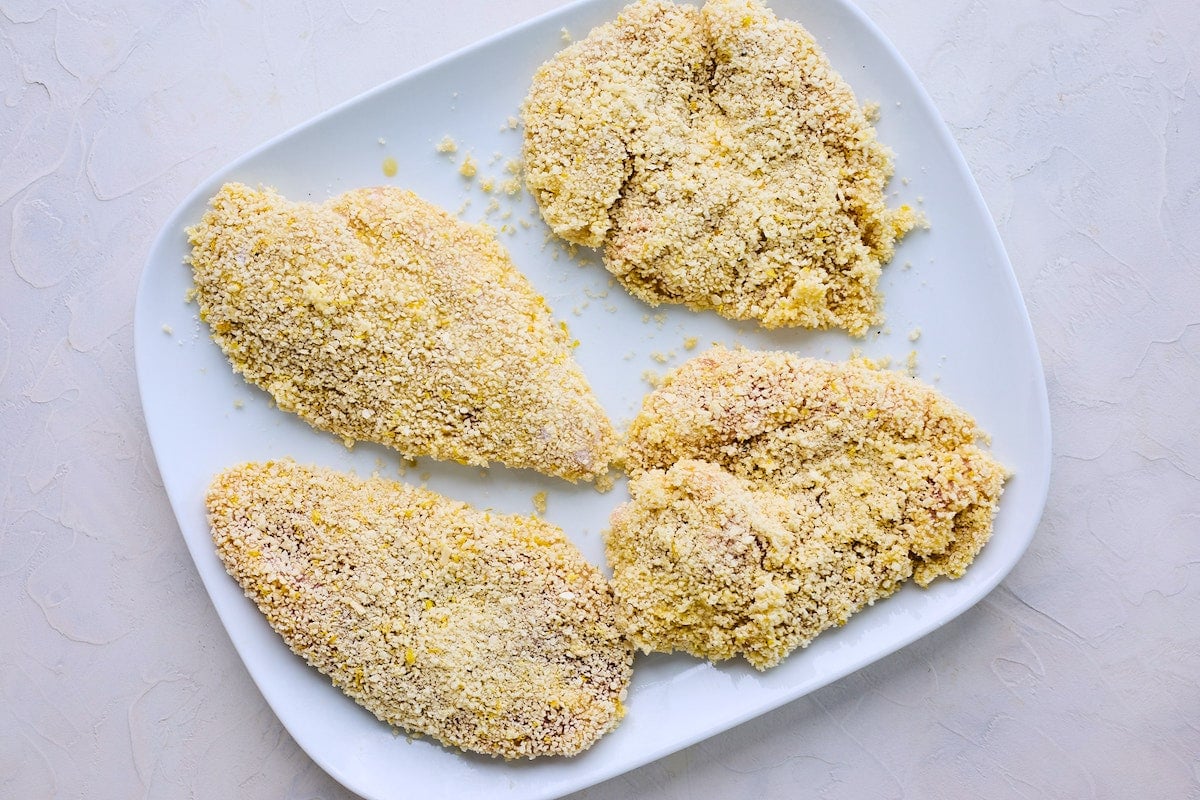 chicken breasts coated in flour and panko on plate to make chicken piccata.