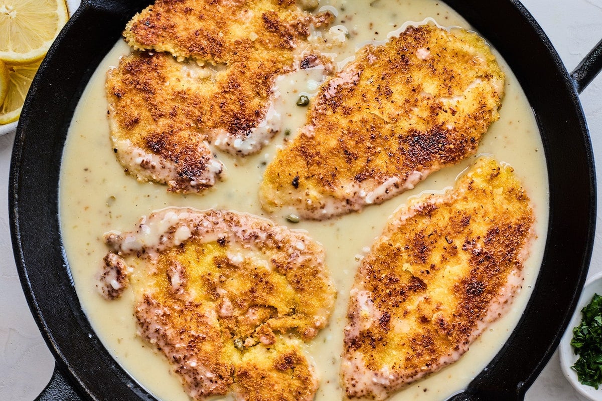 crispy chicken breasts in lemon butter sauce in cast iron skillet.