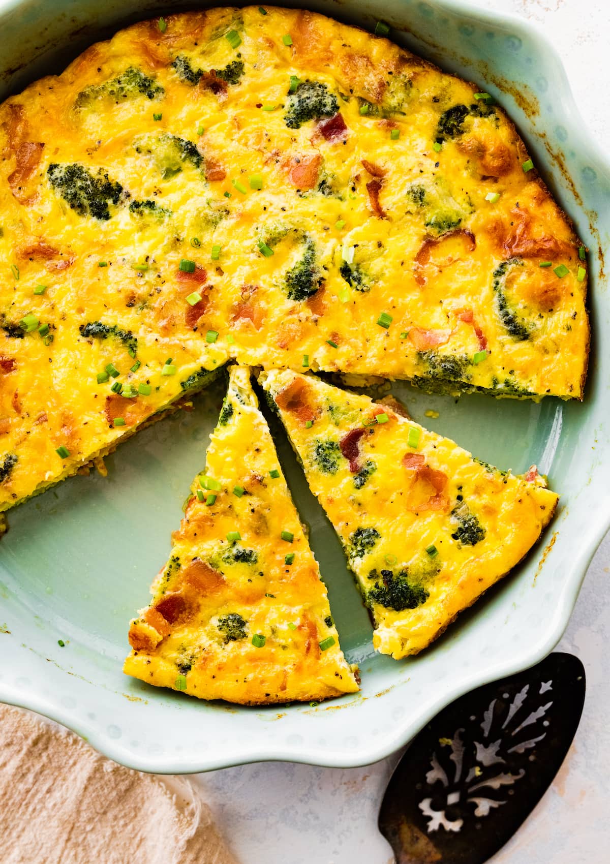 crustless quiche cut into pieces in pie pan.