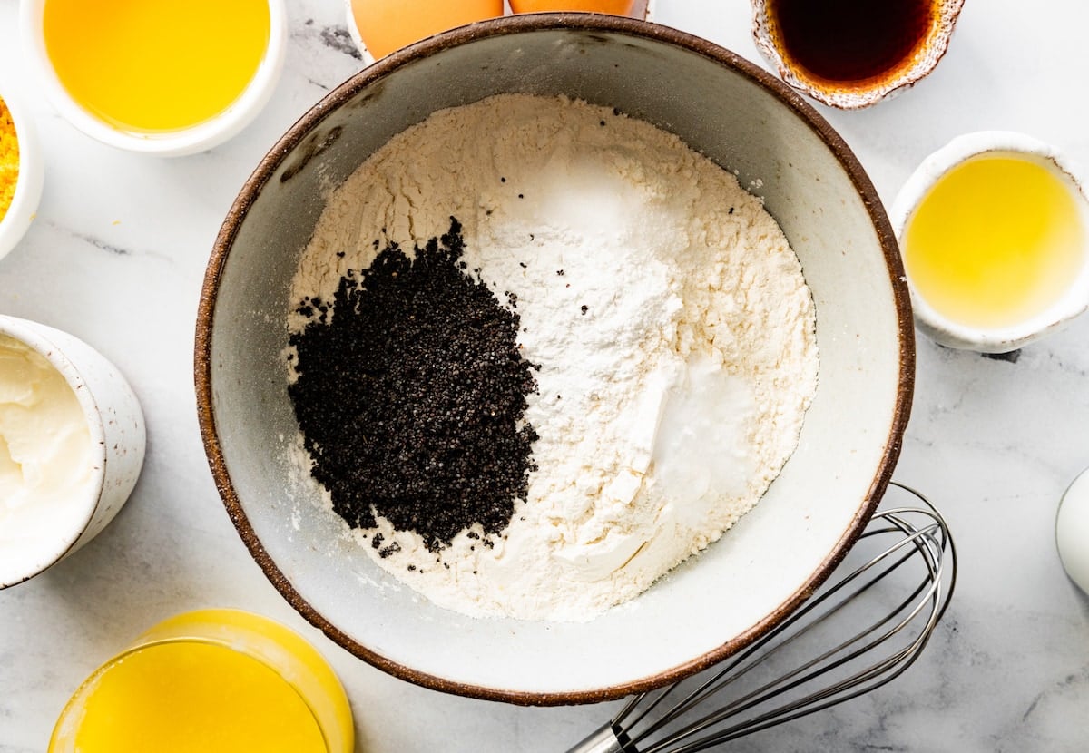 flour, baking soda, baking powder, salt, and poppy seeds in mixing bowl to make lemon poppy seed muffins.