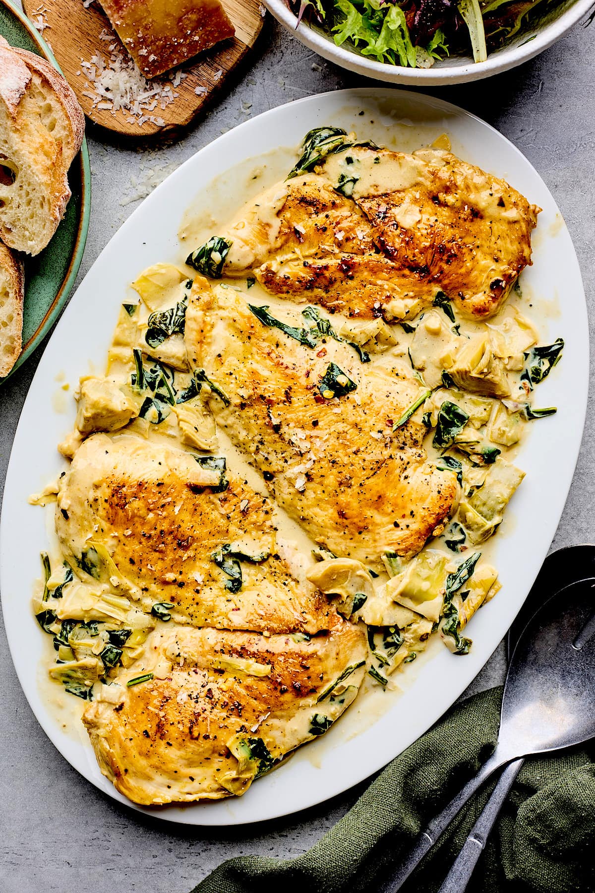 spinach artichoke chicken on large white platter.