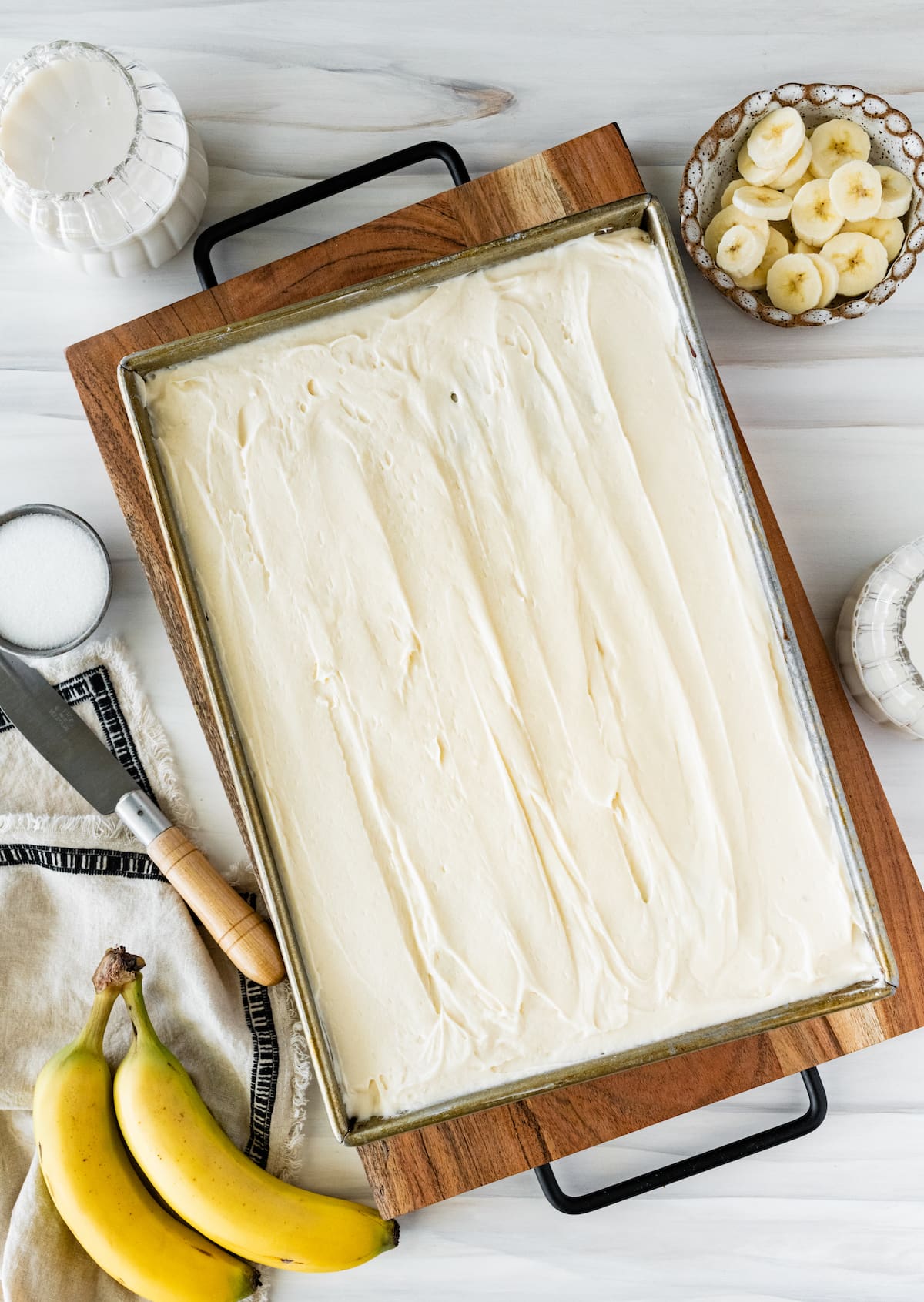 banana cake with cream cheese frosting in pan.
