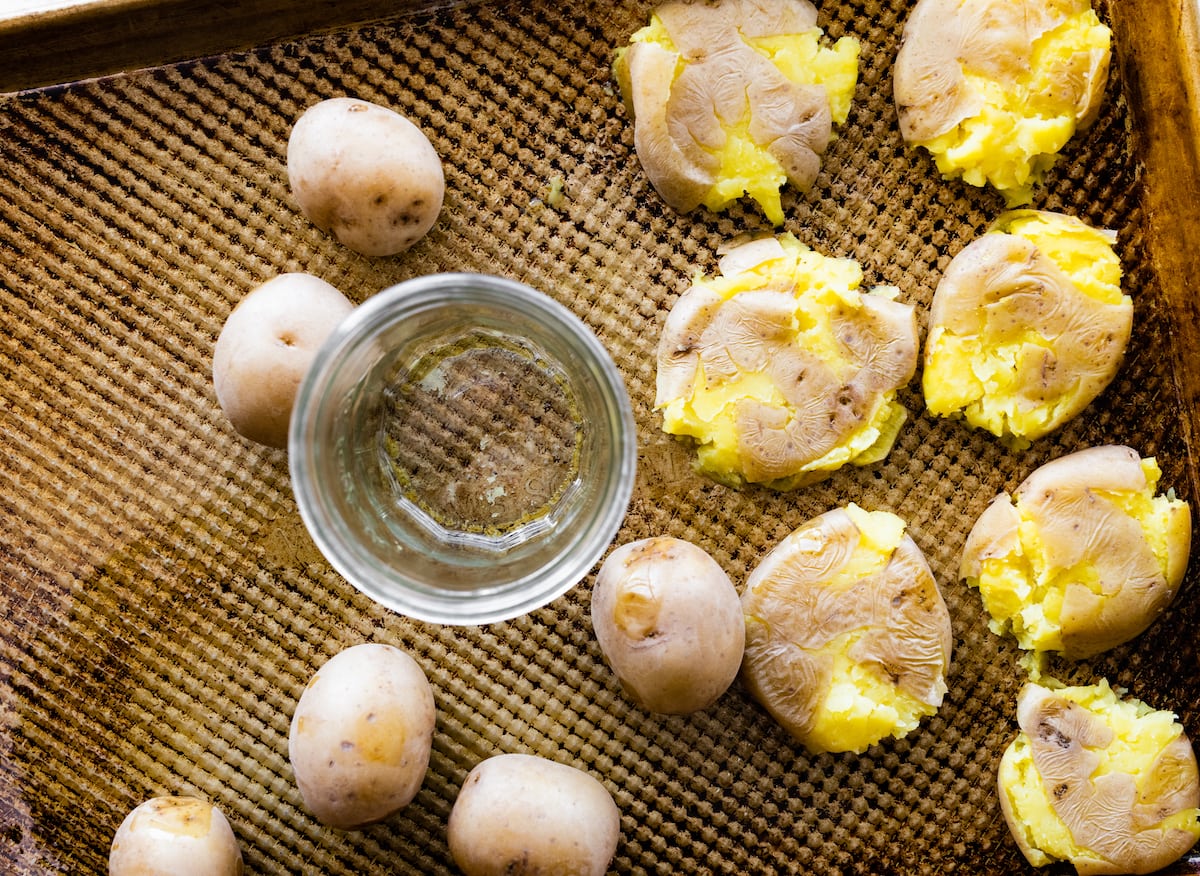 smashing potatoes on baking sheet with glass.