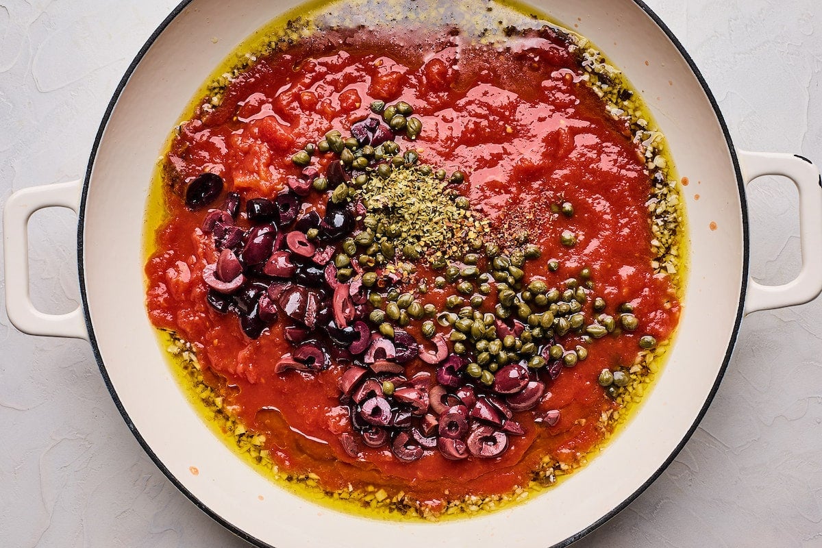 olive oil, tomatoes, olives, dried herbs, and capers in skillet to make pasta puttanesca sauce.