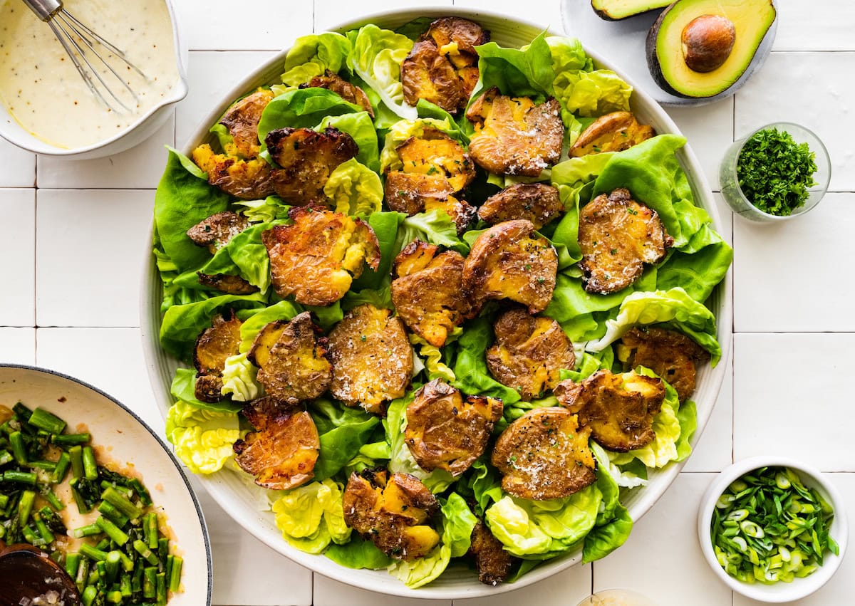crispy smashed potatoes on top of butter lettuce in white bowl.