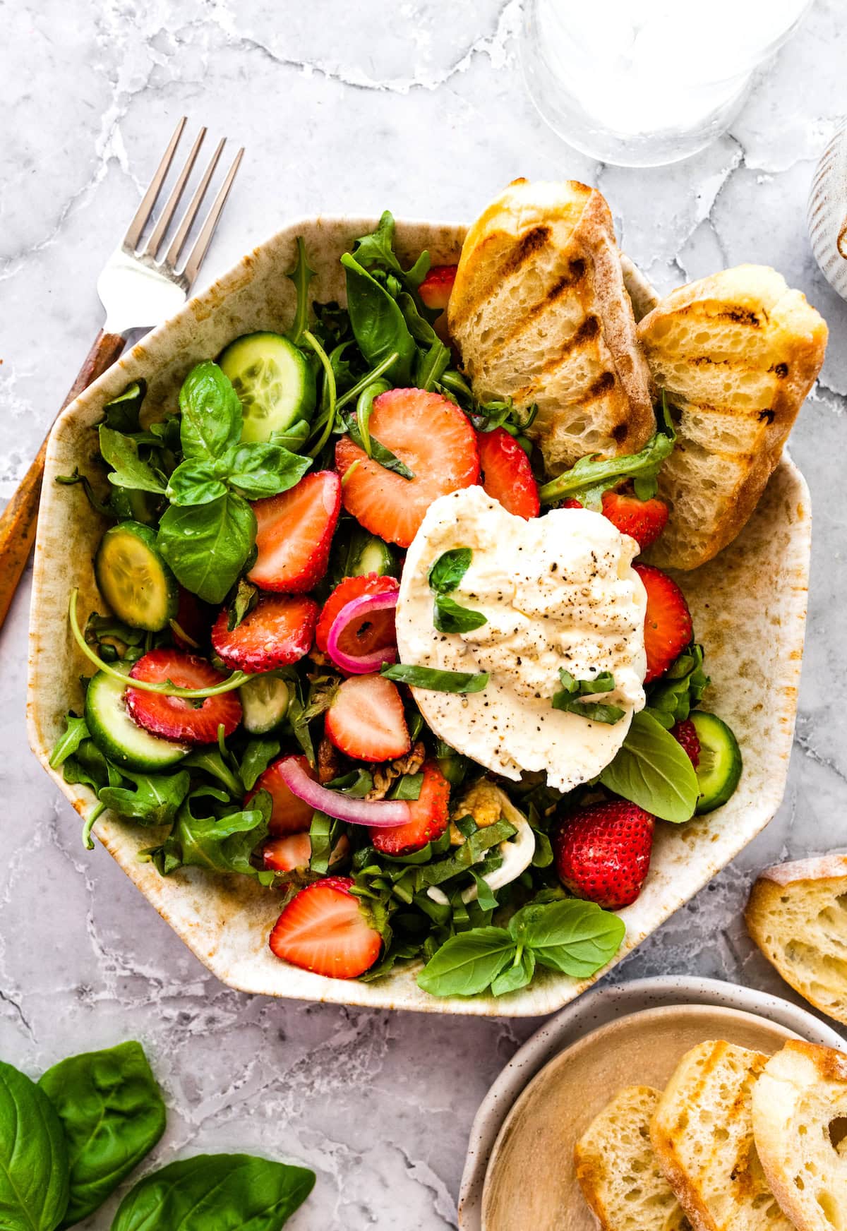 strawberry burrata salad in bowl with grilled bread.