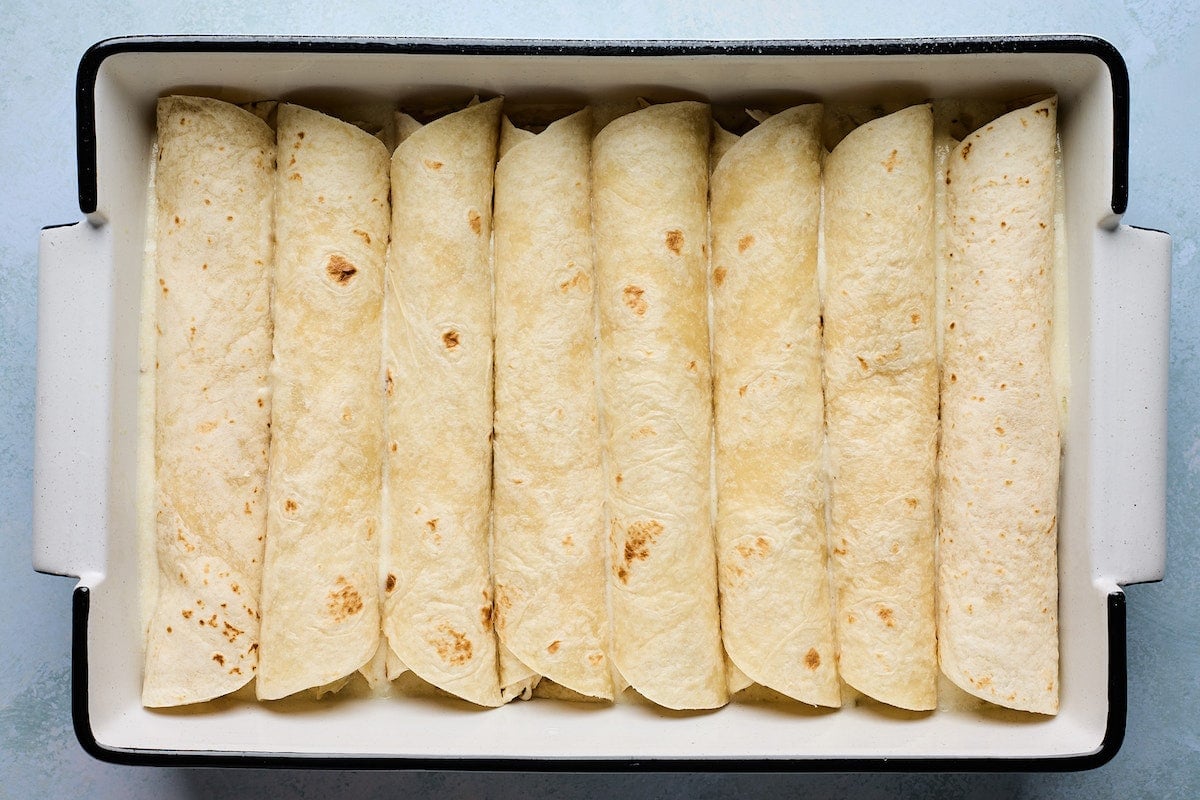 white chicken enchiladas rolled in pan.