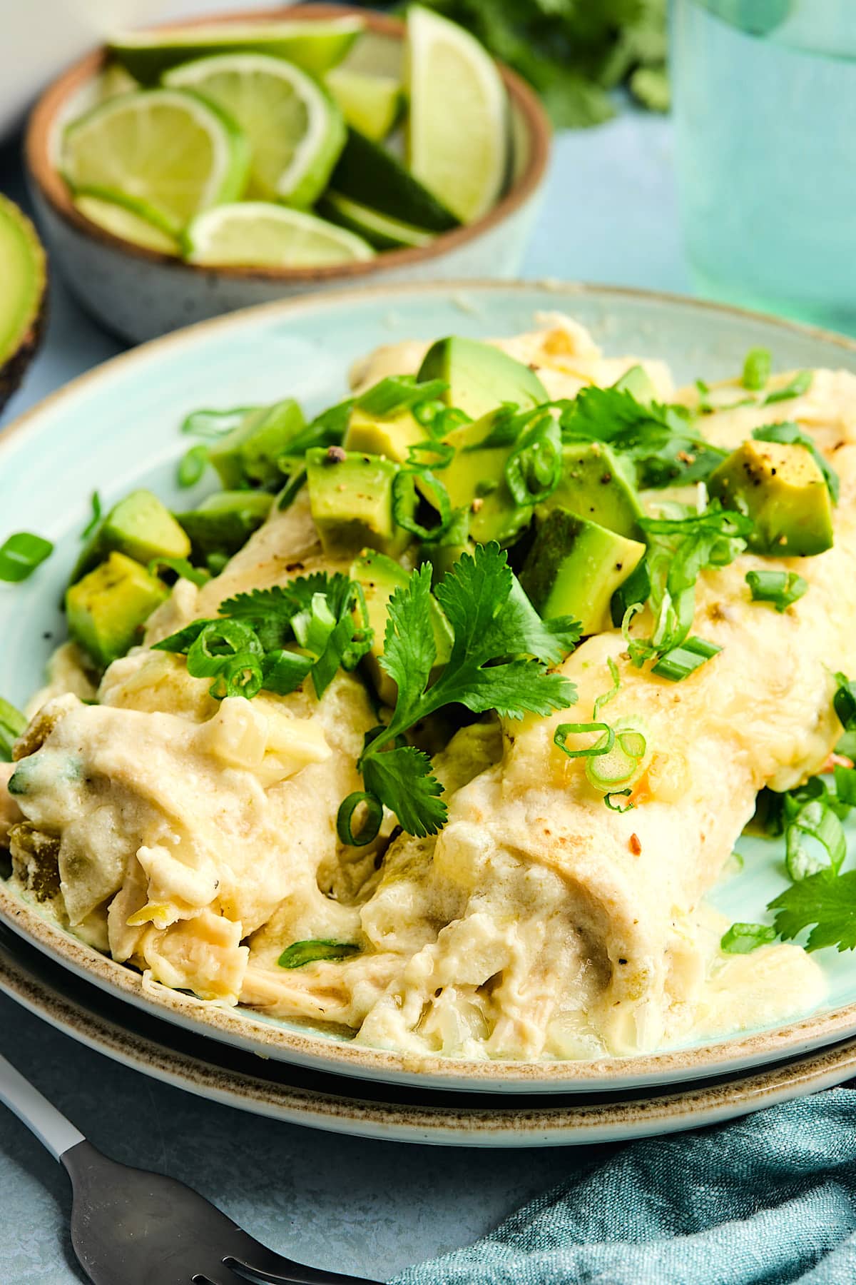 white chicken enchiladas on plate with toppings.