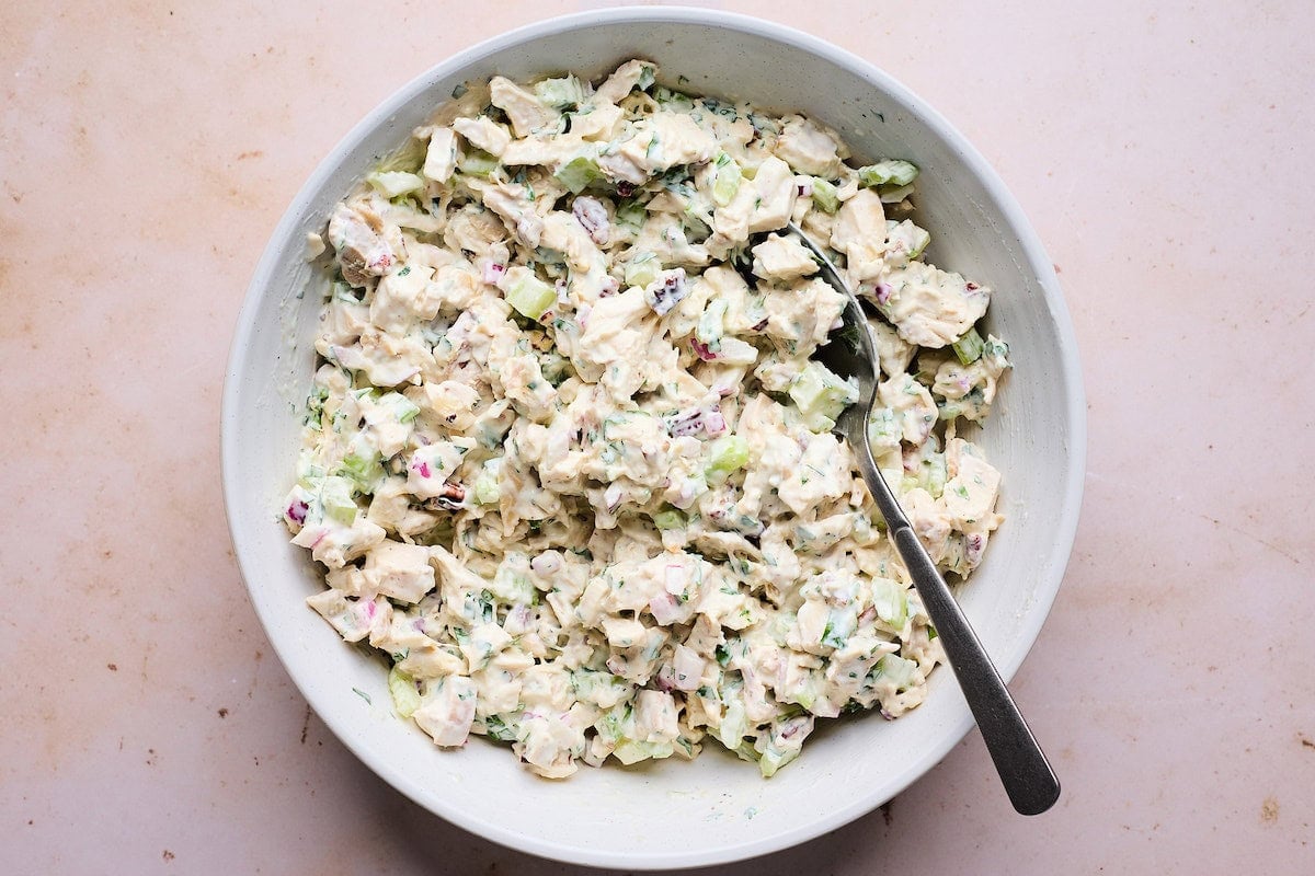 chicken salad in mixing bowl with spoon.