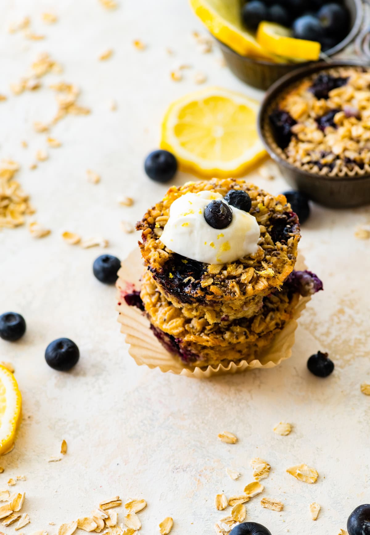lemon blueberry baked oatmeal cups stacked with dollop of Greek yogurt, blueberries, and lemon zest.