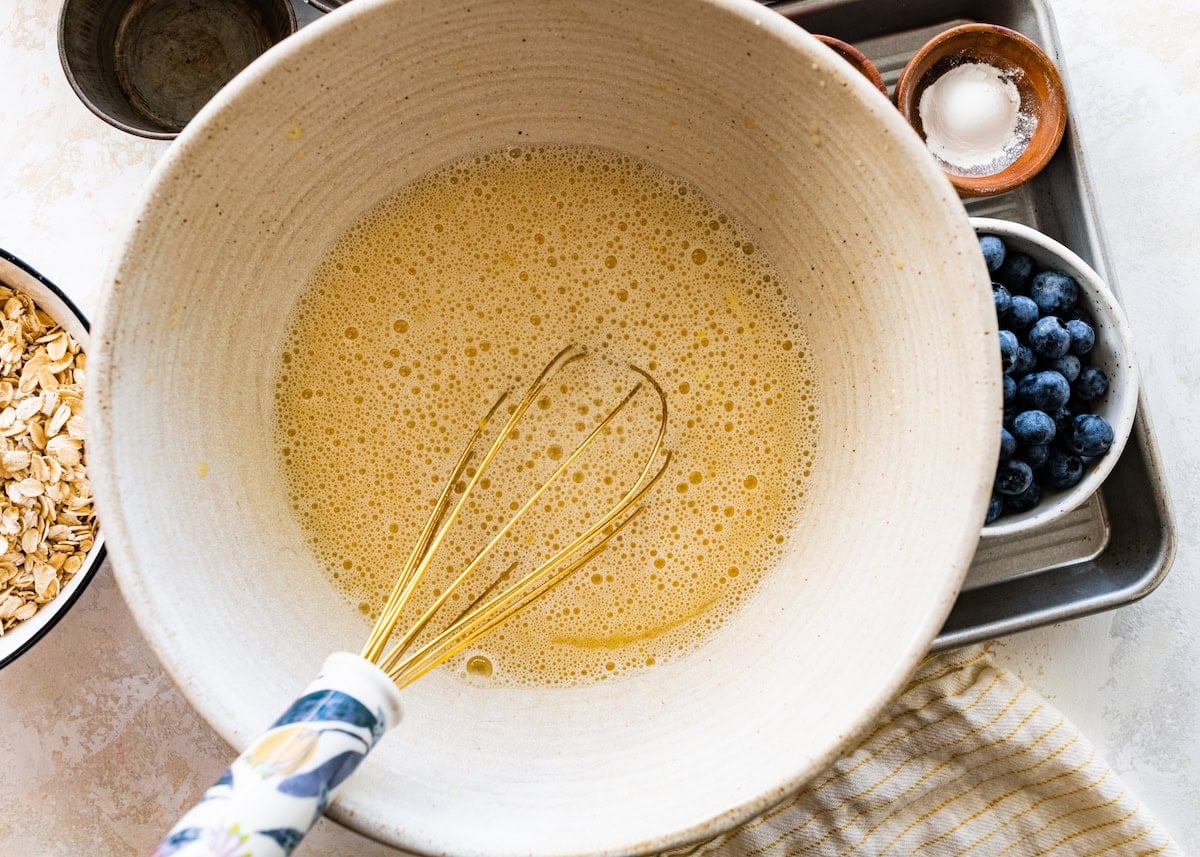 wet ingredients being whisked together in mixing bowl to make lemon blueberry baked oatmeal cups.