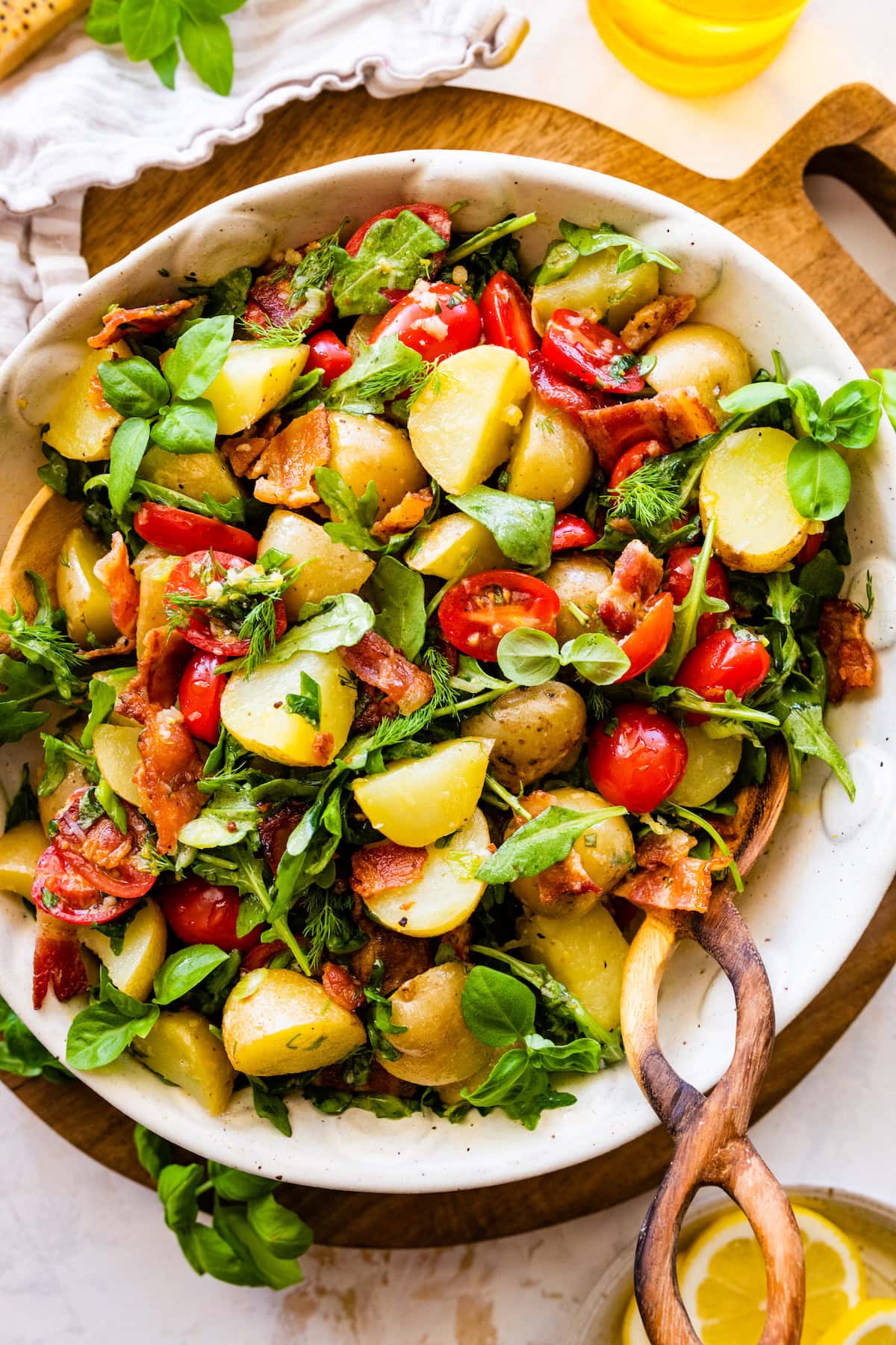 potato salad with bacon, arugula, tomatoes, herbs, and Parmesan cheese in bowl.
