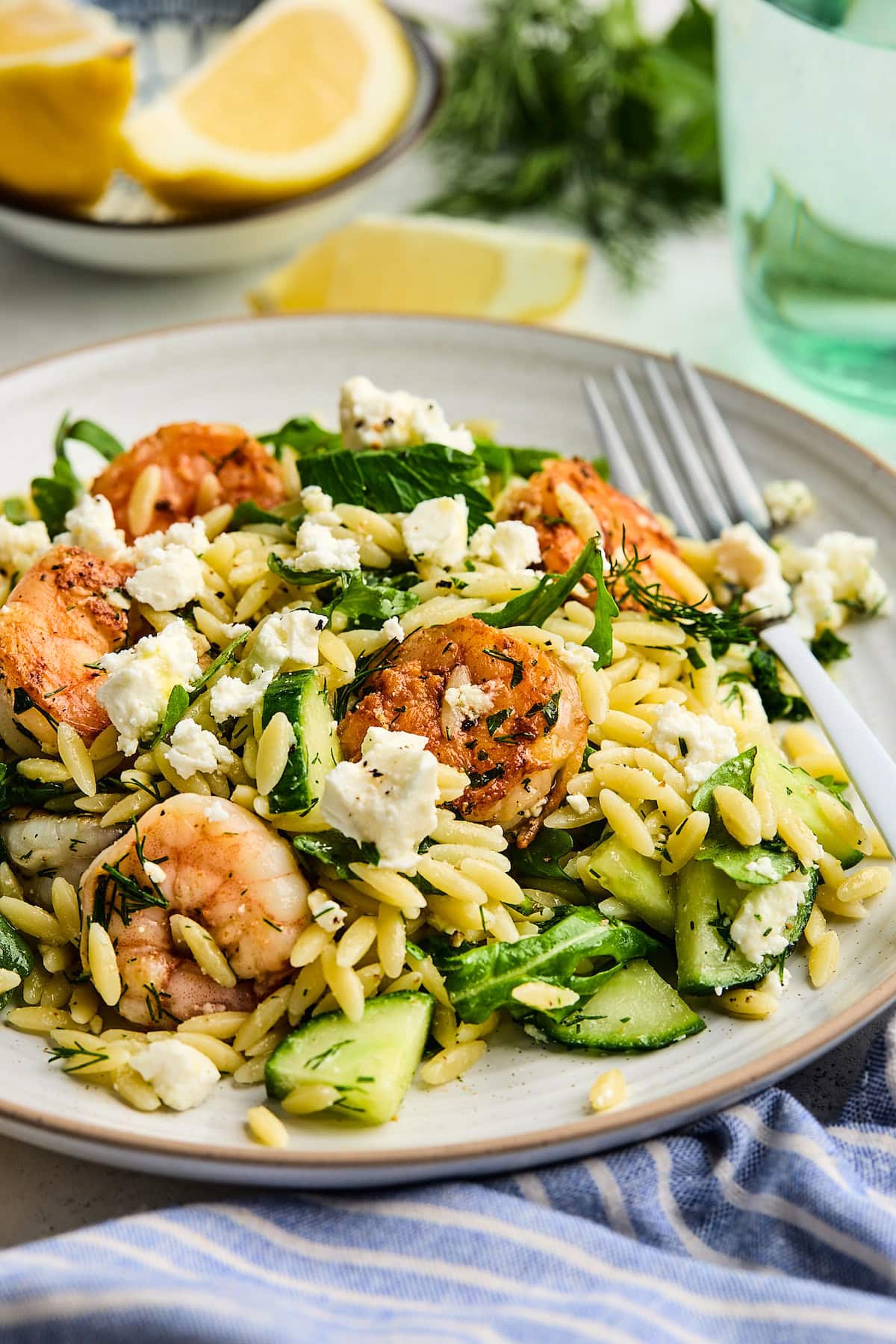 close up of shrimp orzo salad on plate with fork.