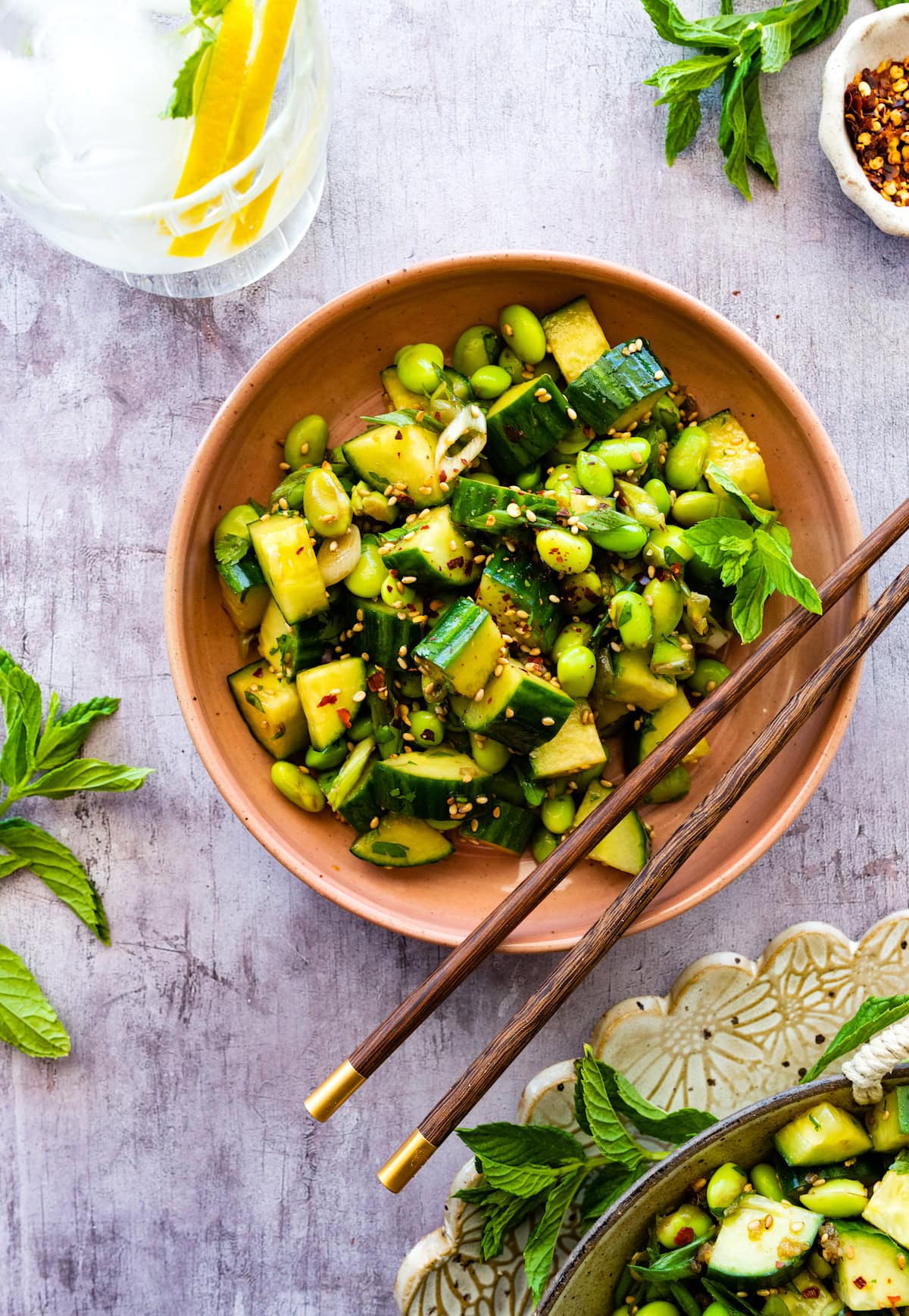 cucumber edamame salad in bowl with chopsticks.