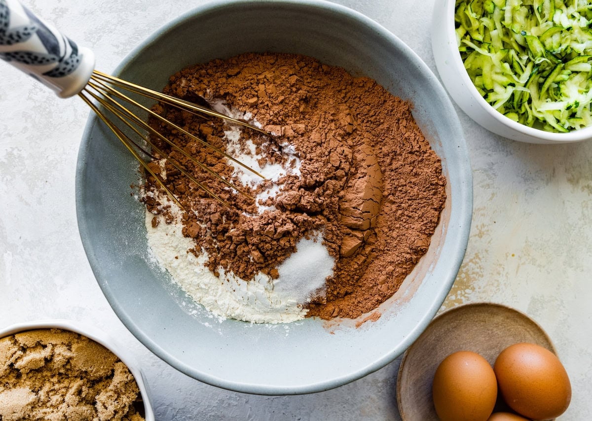 flour, baking soda, salt, and cocoa powder being whisked together in mixing bowl.