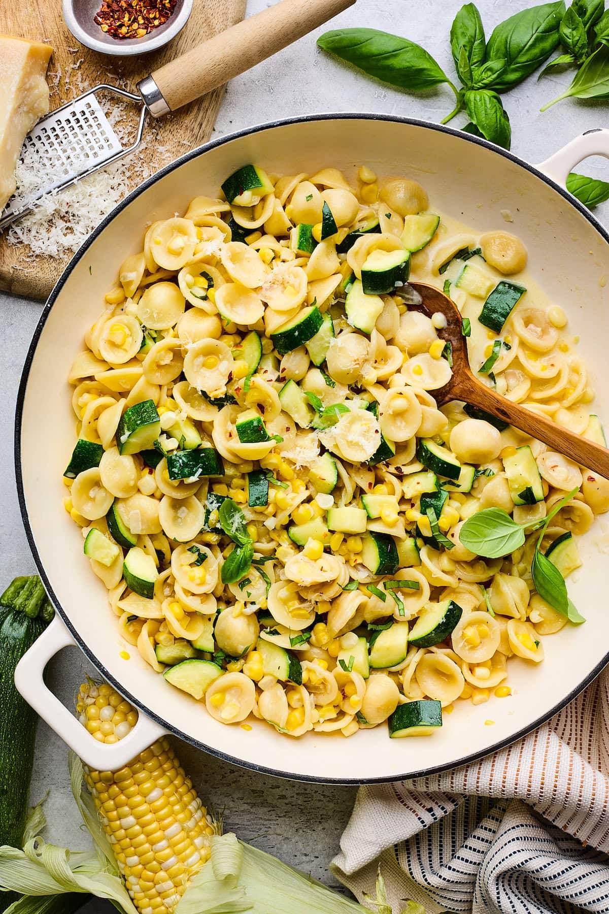 creamy zucchini corn pasta in skillet with wooden spoon.