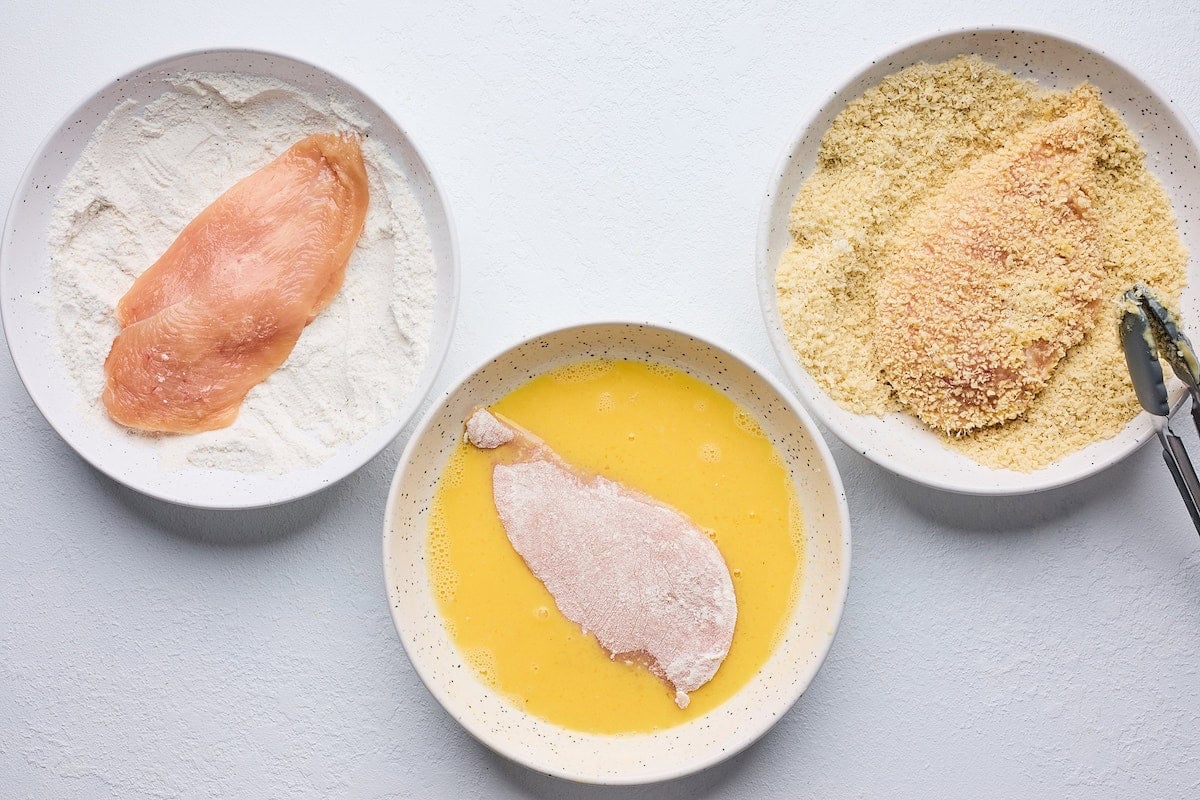 chicken breasts on plates with flour, egg, and panko.