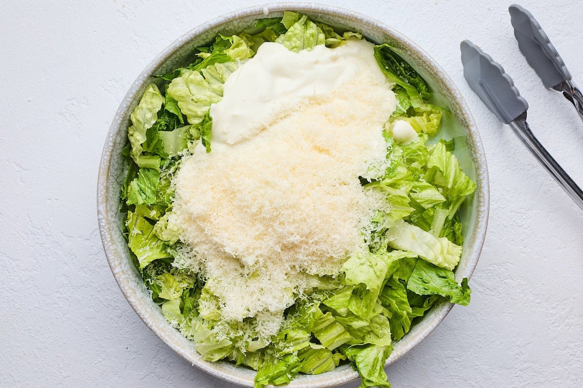 romaine lettuce in bowl with creamy lemon dressing and parmesan cheese.