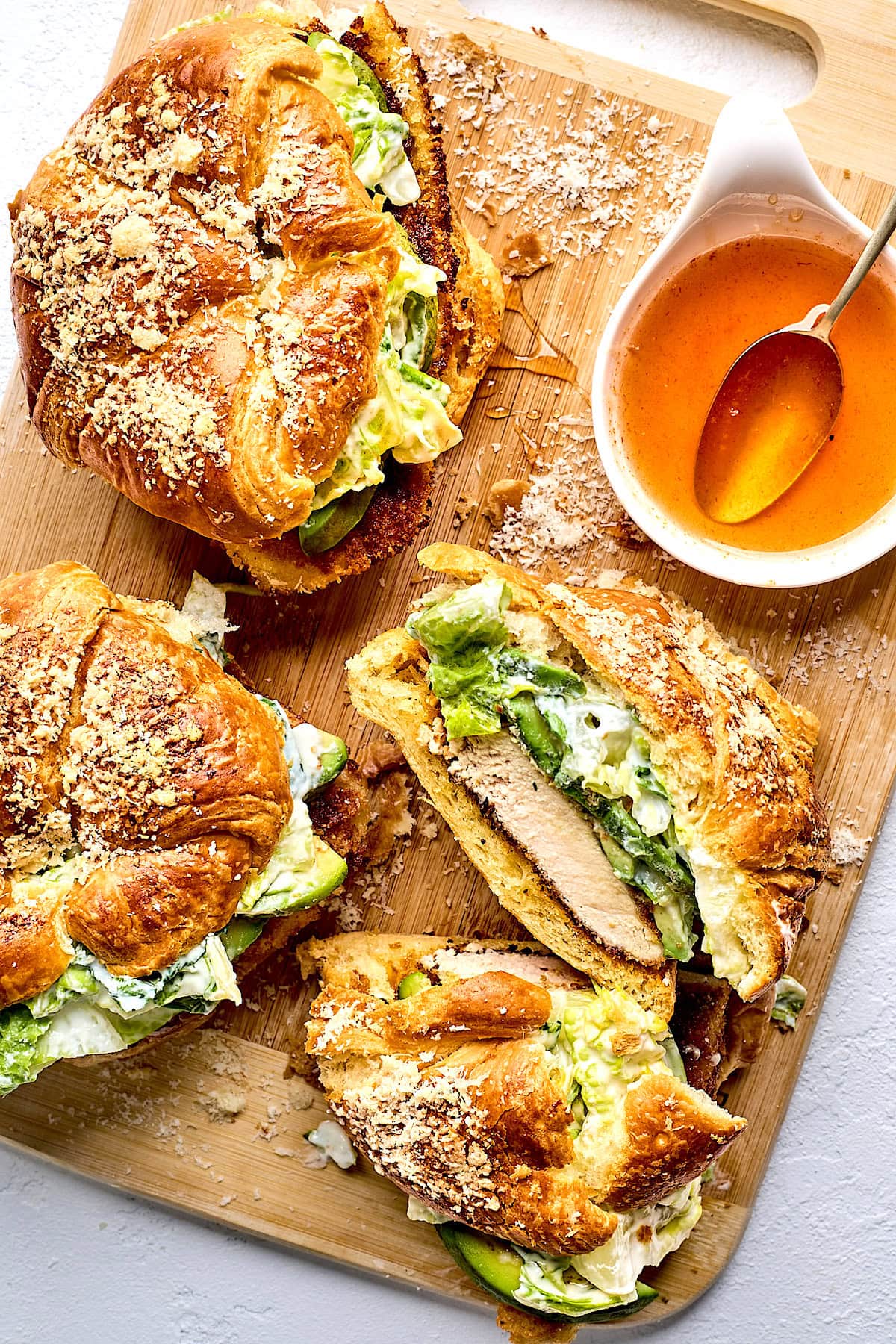 crispy chicken croissant sandwiches with romaine lettuce, avocado, Parmesan cheese, and hot honey.