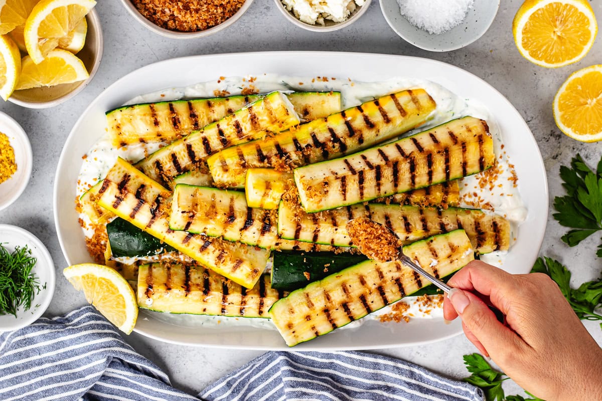 grilled zucchini salad with toasted garlic breadcrumbs being sprinkled on top.