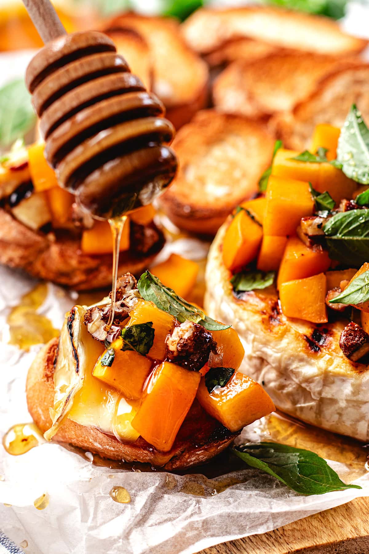 honey being drizzled over grilled brie with peaches on crostini.