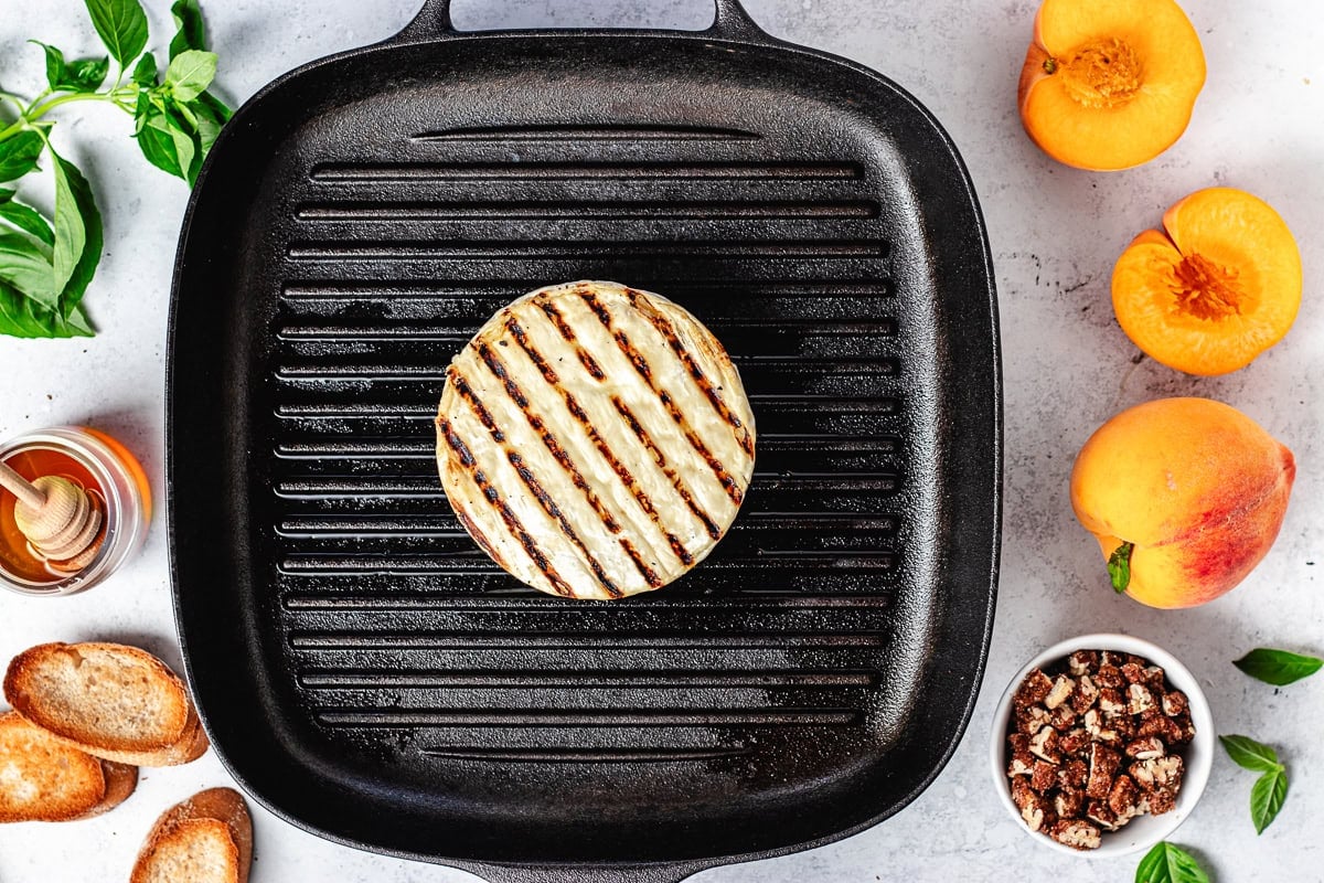 round of brie cheese being grilled on grill pan.