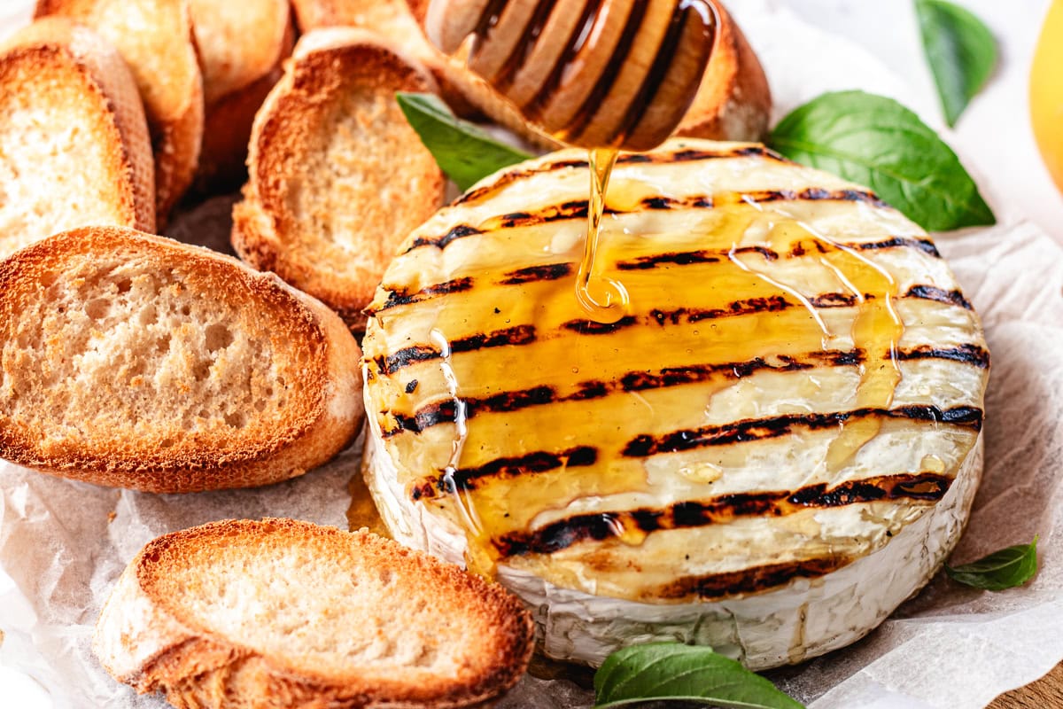 honey being drizzled over grilled brie.