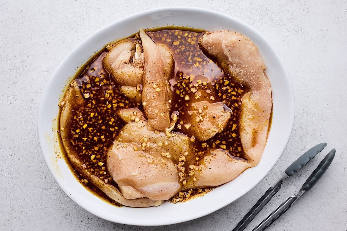 chicken breasts marinating in hot honey marinade on plate.