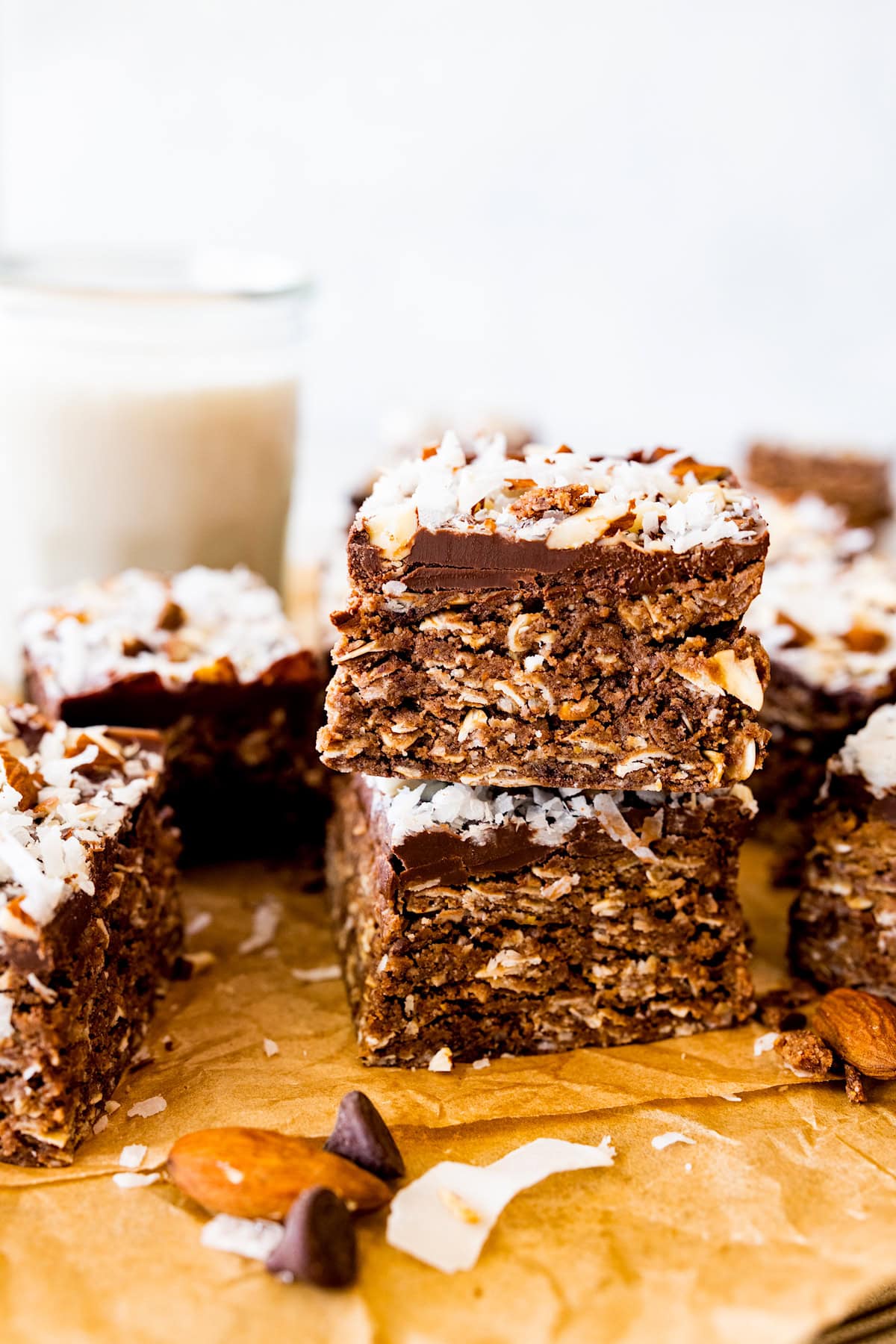 stack of no bake almond joy bars on parchment paper with glass of milk.