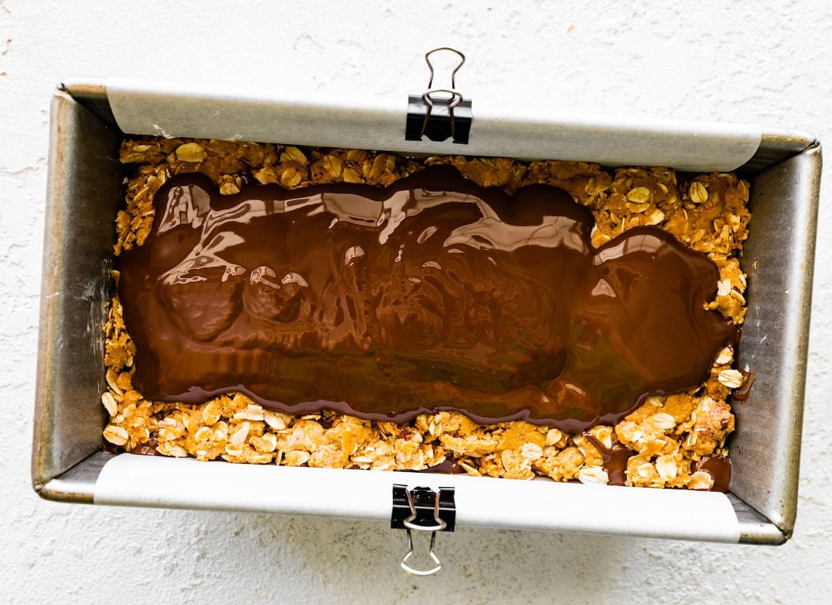 no bake peanut butter s'mores bars being layered in loaf pan.