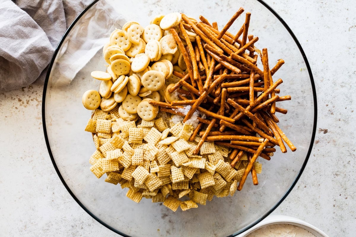 mini peanut butter crackers, pretzels, and rice chex cereal in glass mixing bowl.