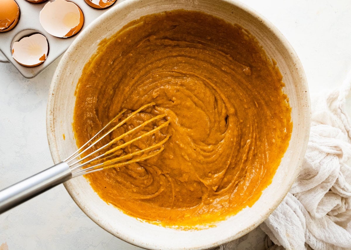 pumpkin cake batter with whisk in mixing bowl.