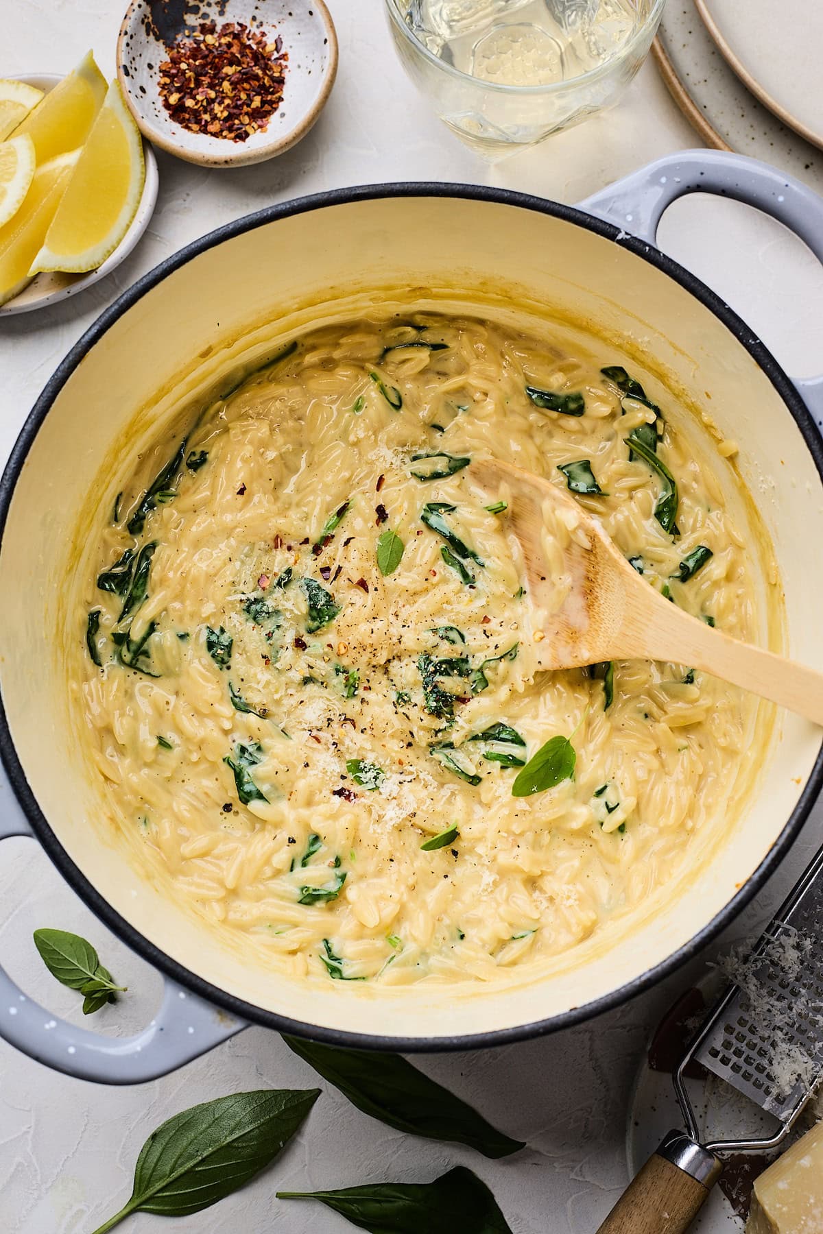 creamy orzo in pot with wooden spoon.